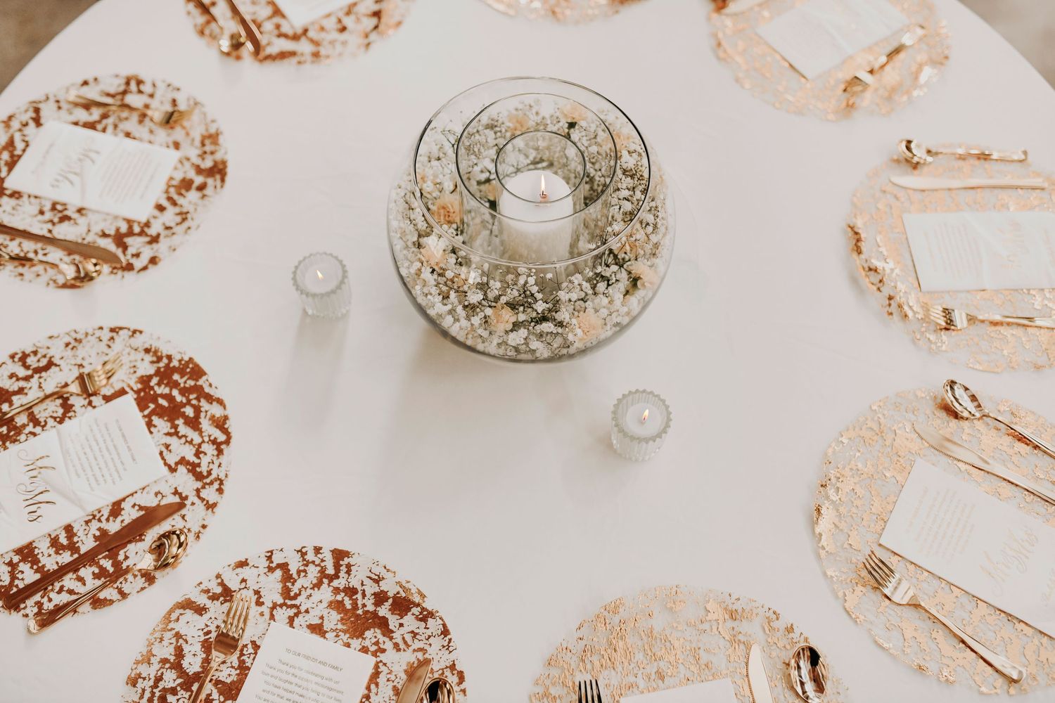 Overhead shot of mismatched candle holders and pastel napkins on barn wood table