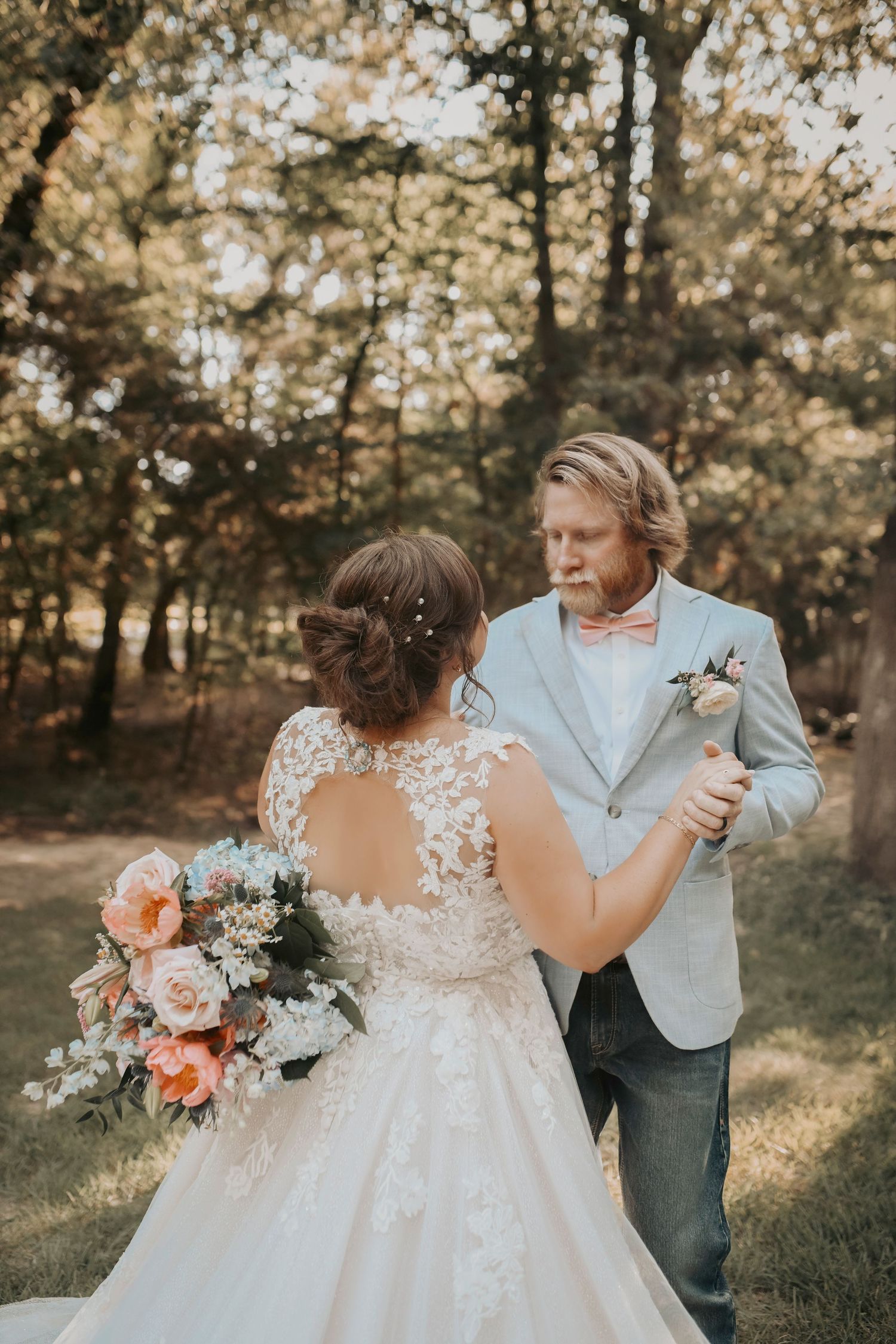 Magical golden hour kiss between bride and groom under leafy branches