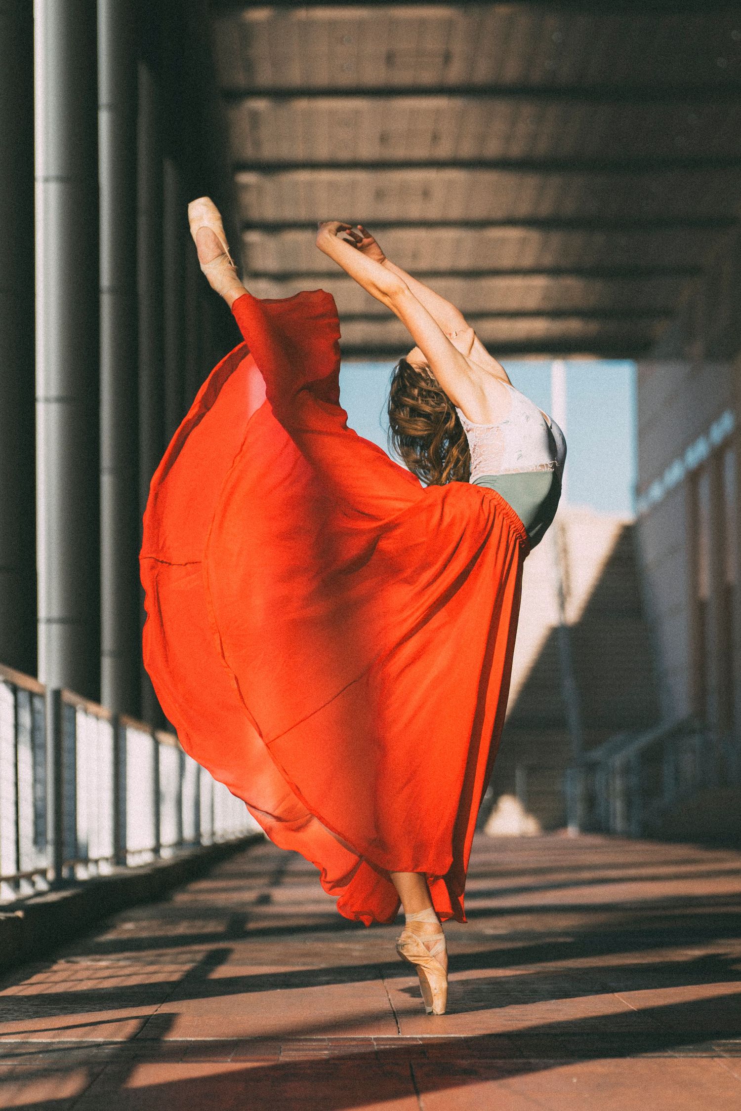 tampa ballet dance photography with ballerina in red skirt and leotard in pointe shoes extending her leg behind her back