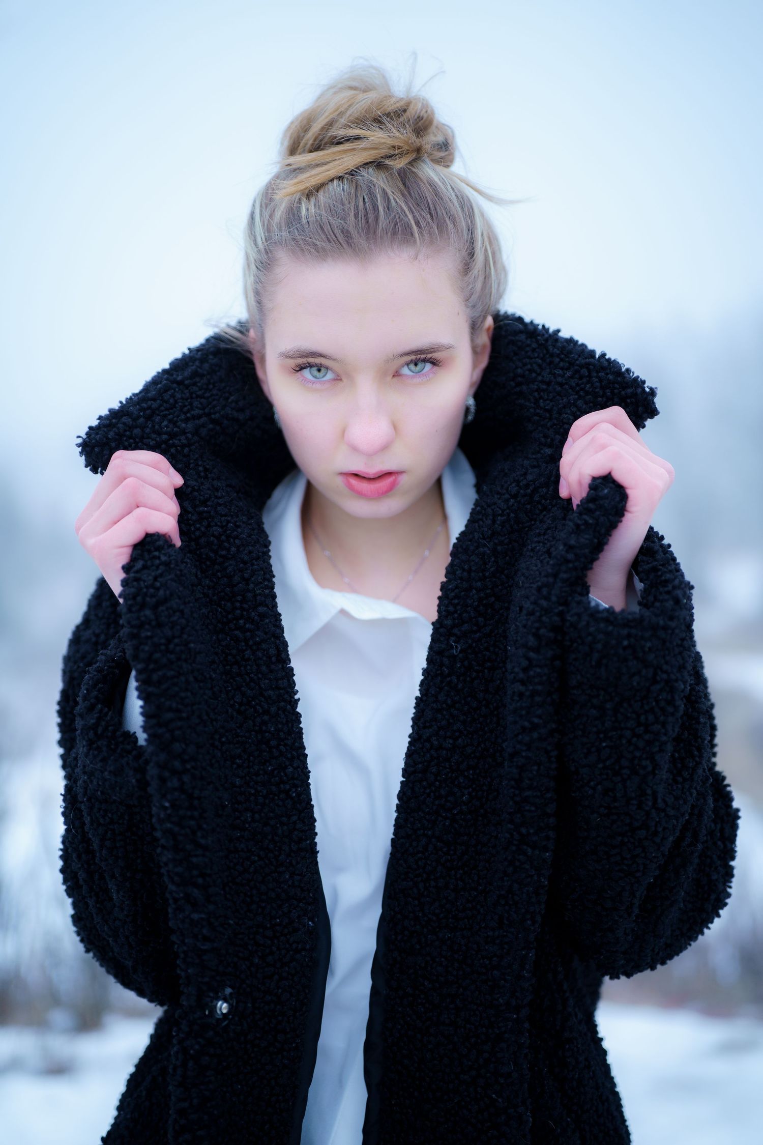 Person wearing a cozy black teddy coat and white top poses against a light winter background.