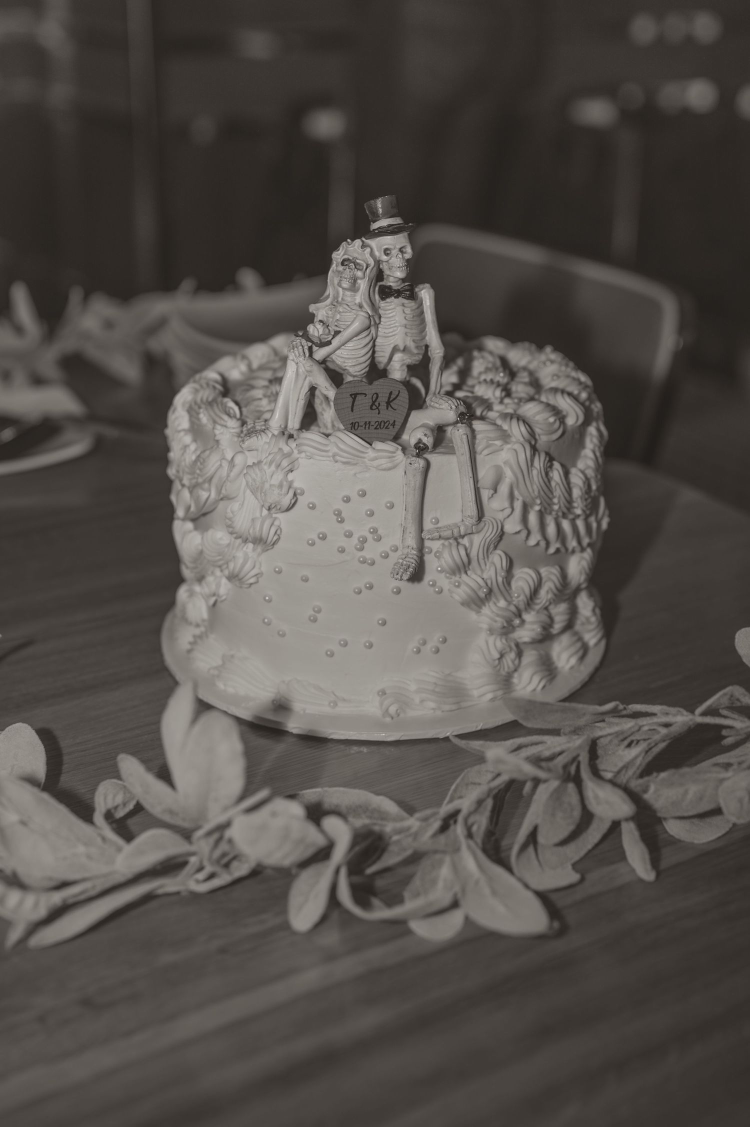 Black and white photo by Samantha Campbell of a vintage wedding cake topper figurine with ruffled frosting details and decorative elements.