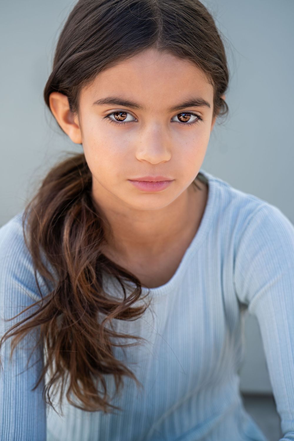 Studio portrait of person in light blue top with long dark hair.