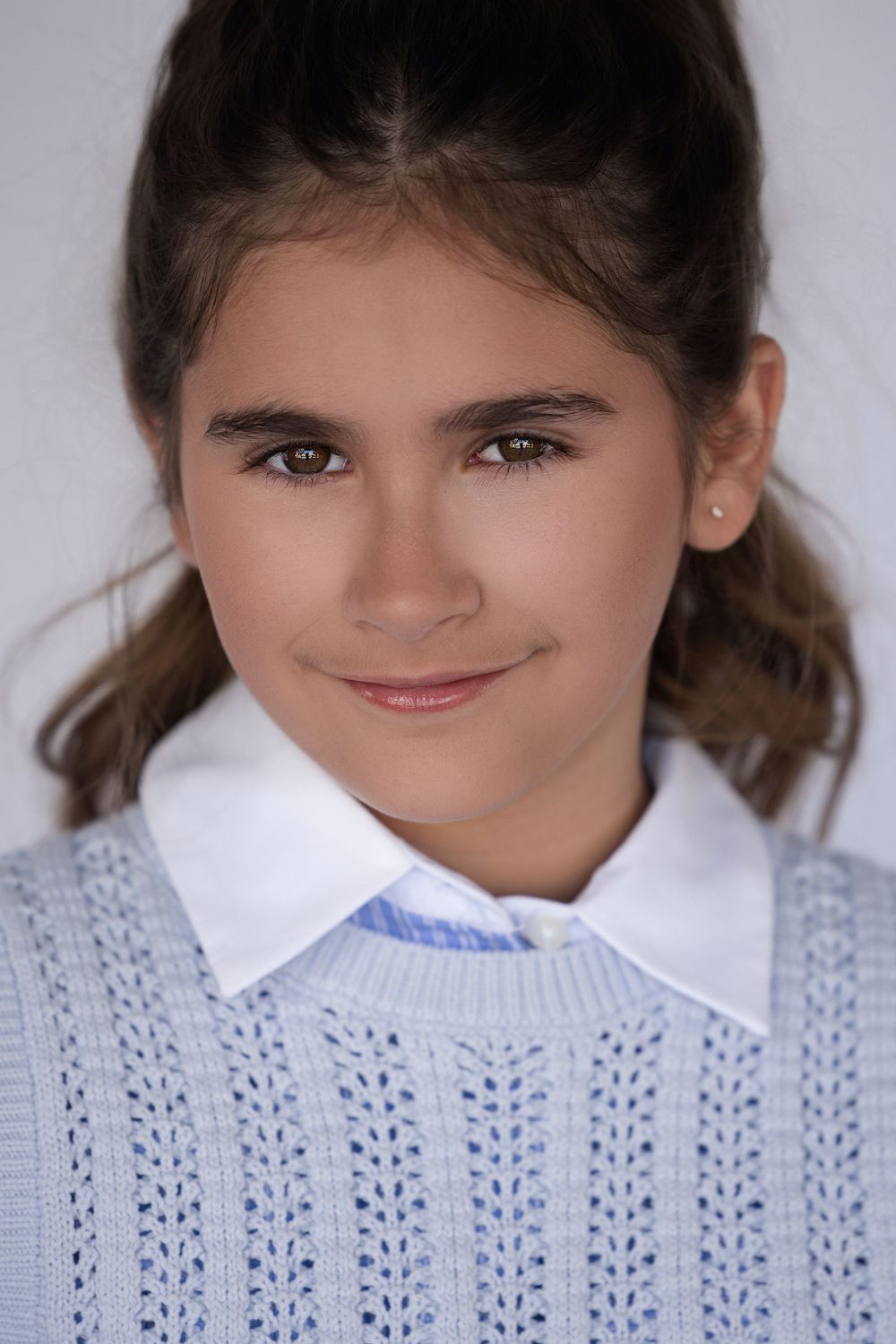 Portrait in a light blue knit sweater with white collar against a studio background.