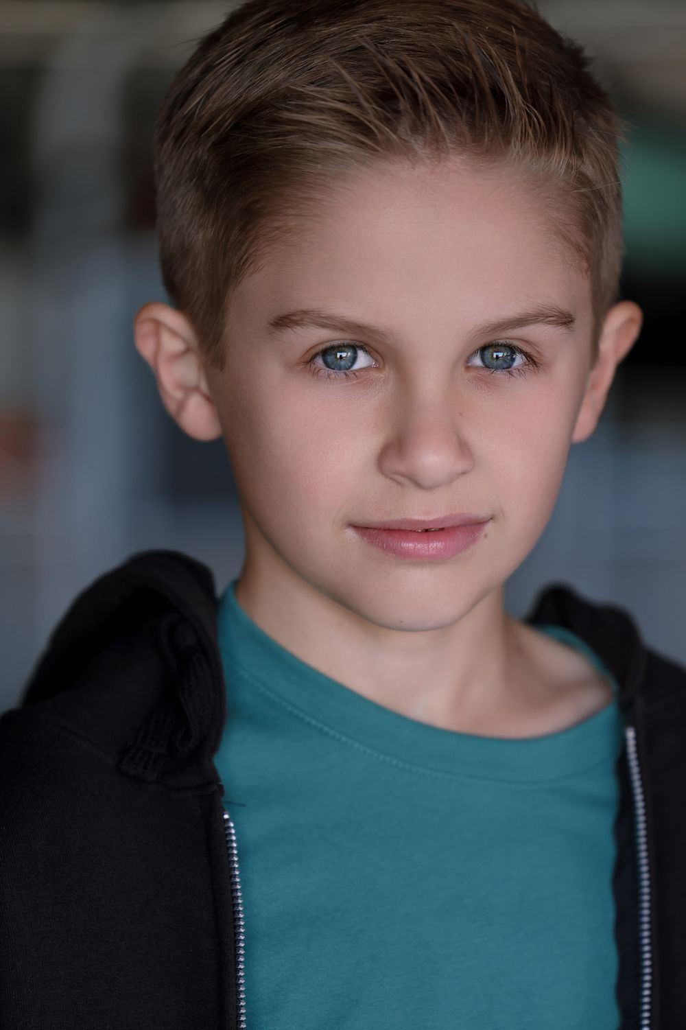 Studio headshot of person in black hoodie and teal shirt.