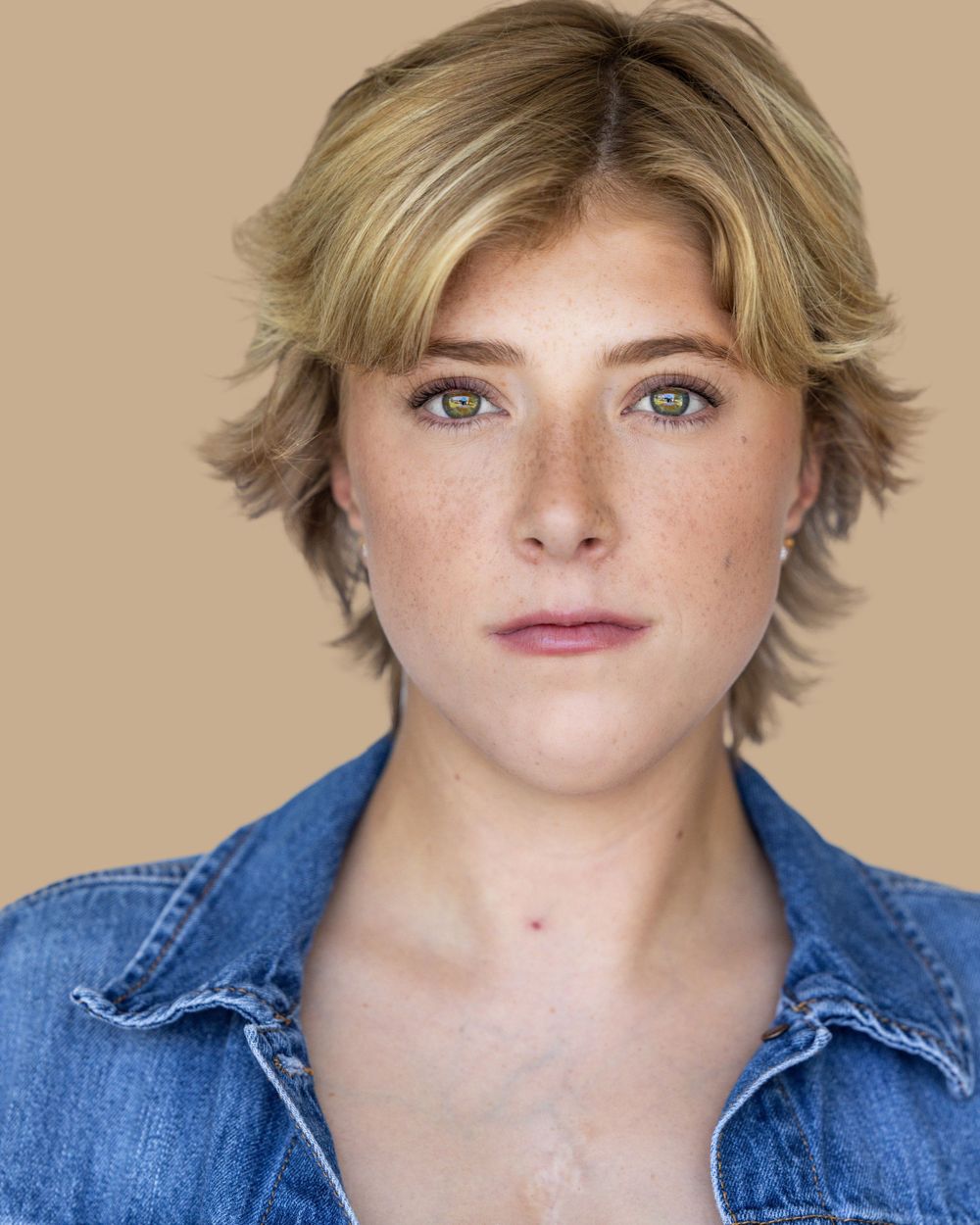 Headshot of person with short blonde hair in denim shirt.
