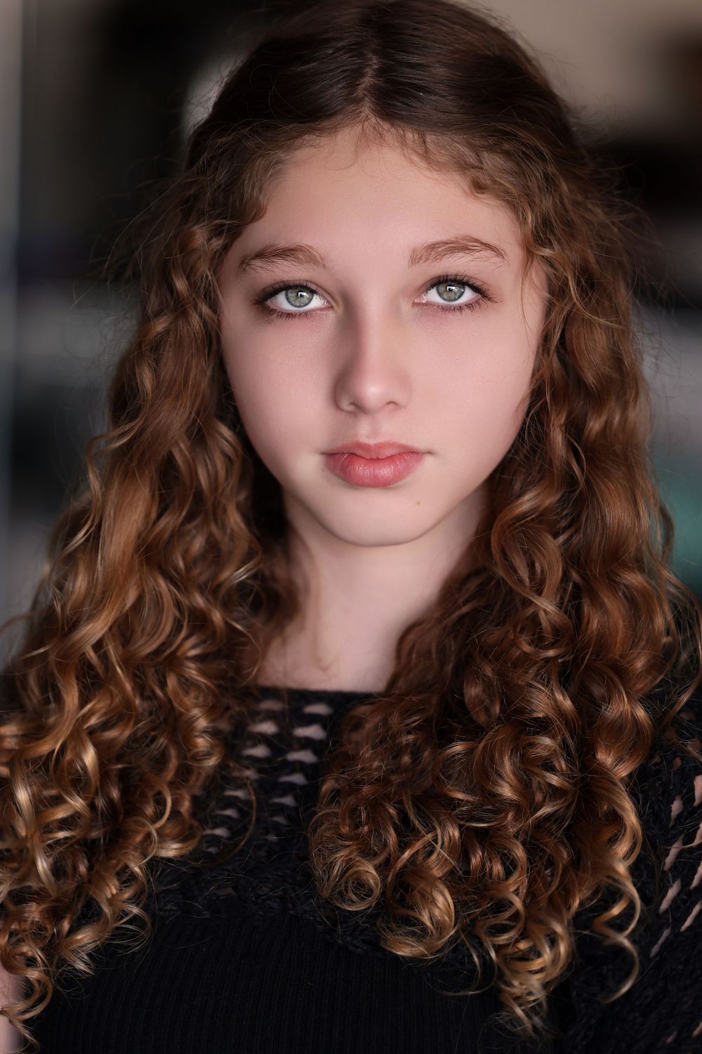 Studio portrait of person with long curly hair in black top.