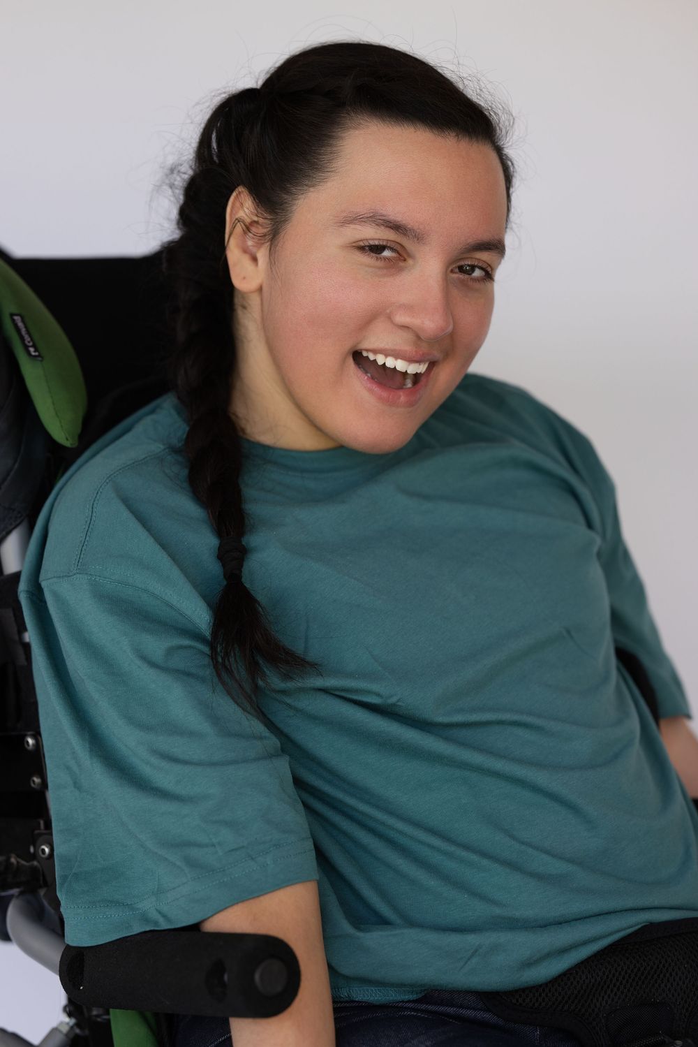 Casual portrait in a teal t-shirt with braided black hair and bright smile.