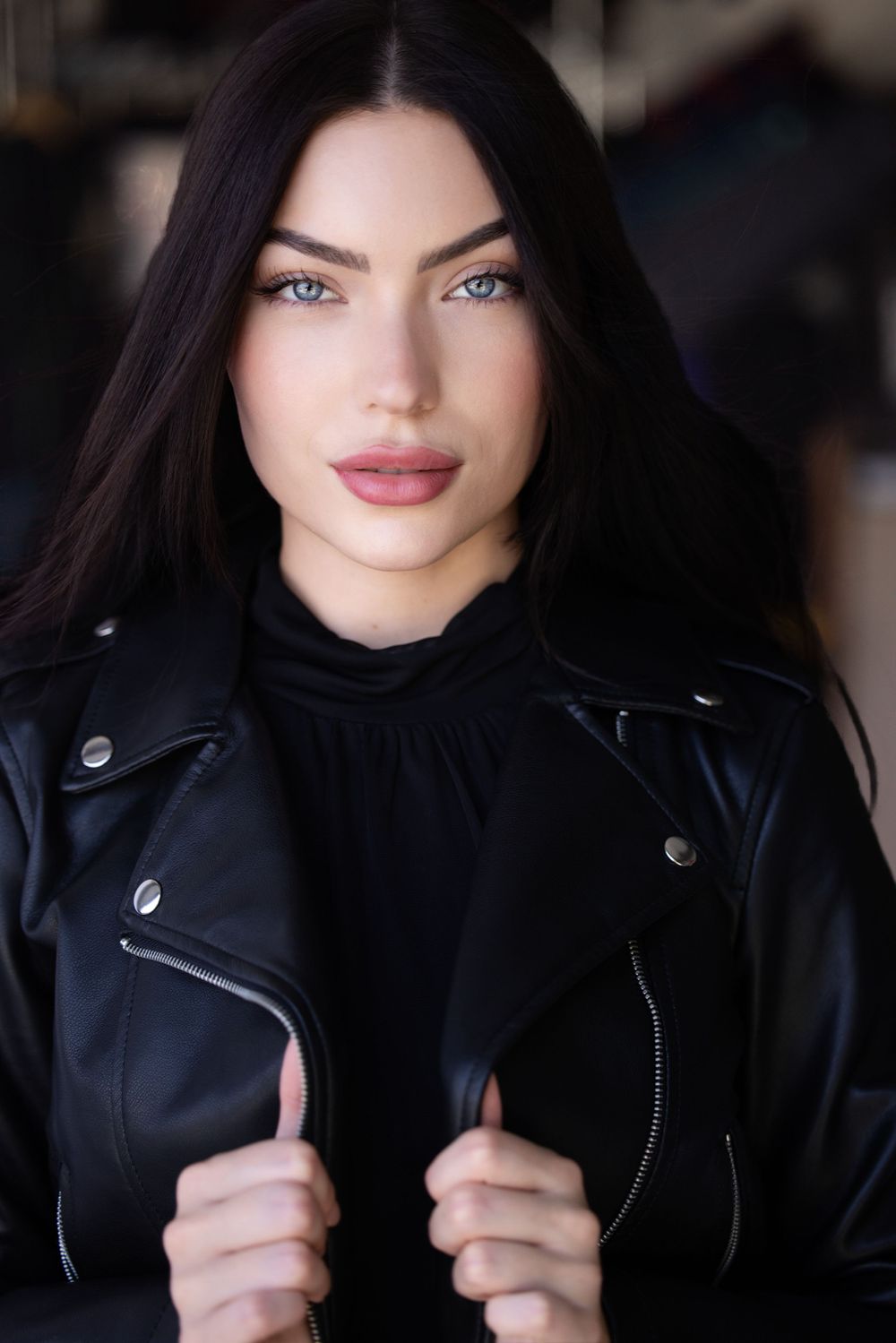 Fashion portrait in a black leather jacket and dark top with striking makeup.