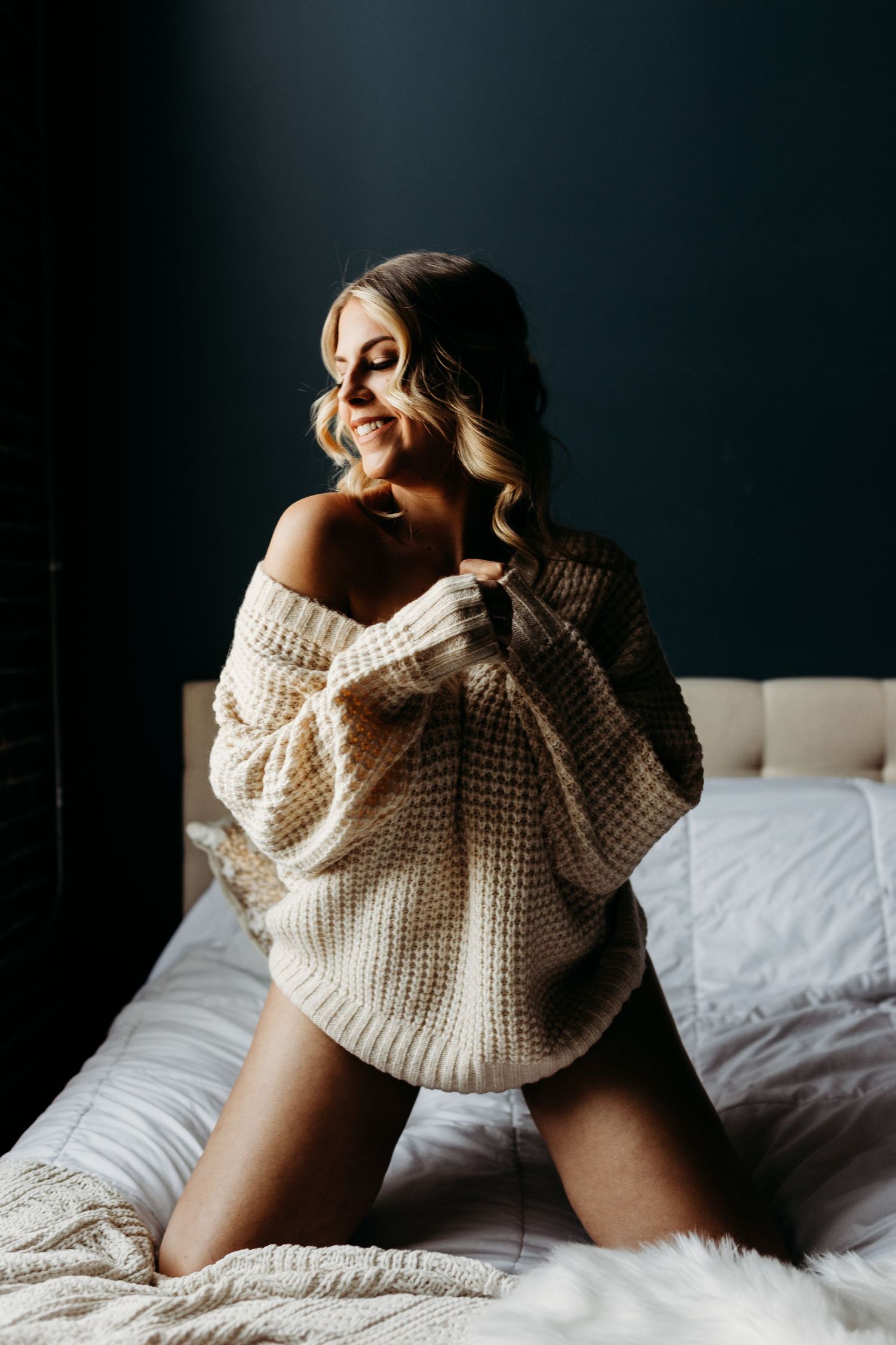 Intimate portrait in oversized knit sweater with dramatic window lighting.