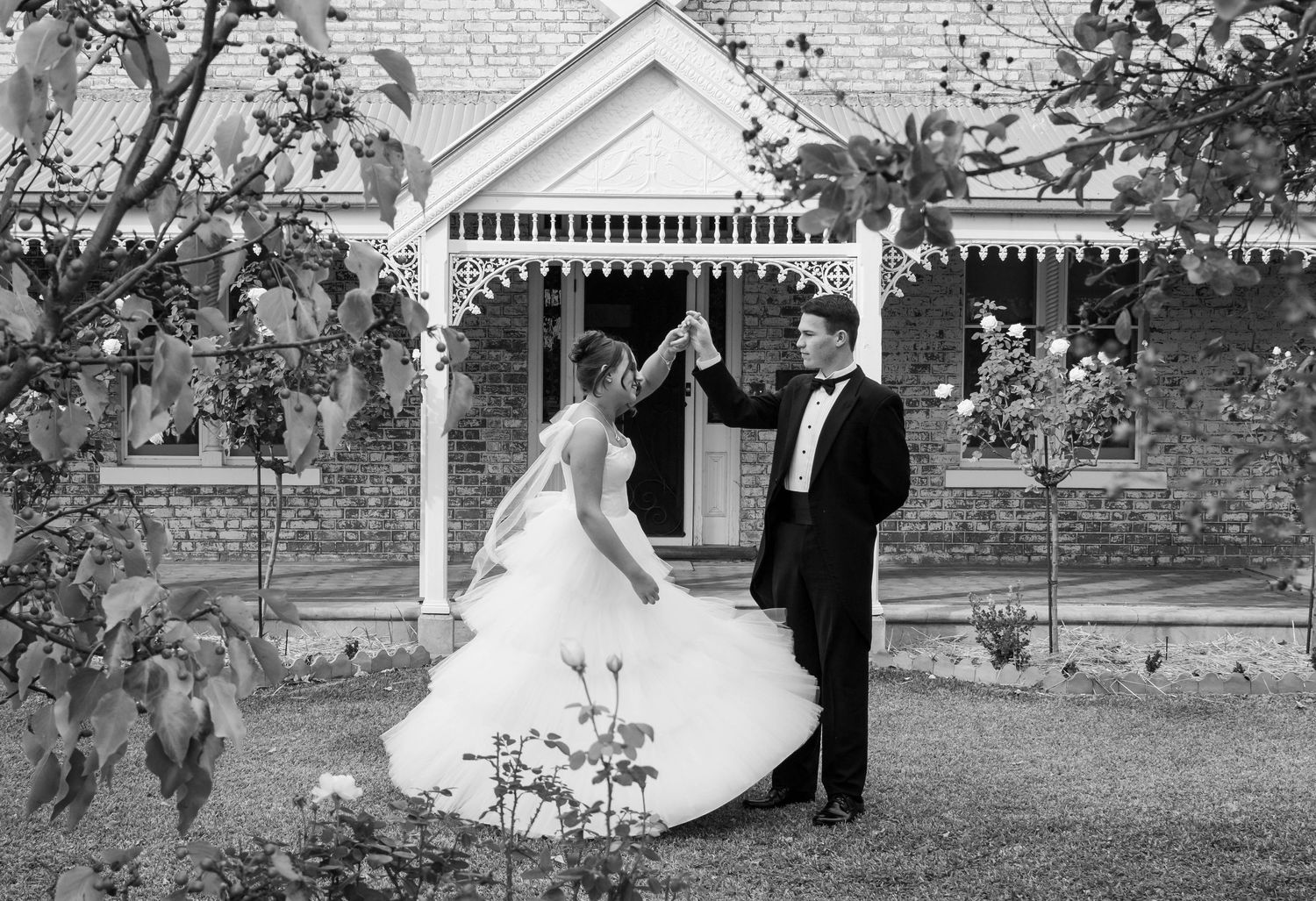 A black and white photo of a deb couple dancing by a vintage gazebo.