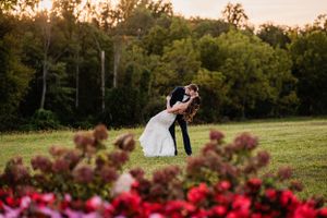 A romantic sunset wedding photo with couple embracing among flowers in foreground.