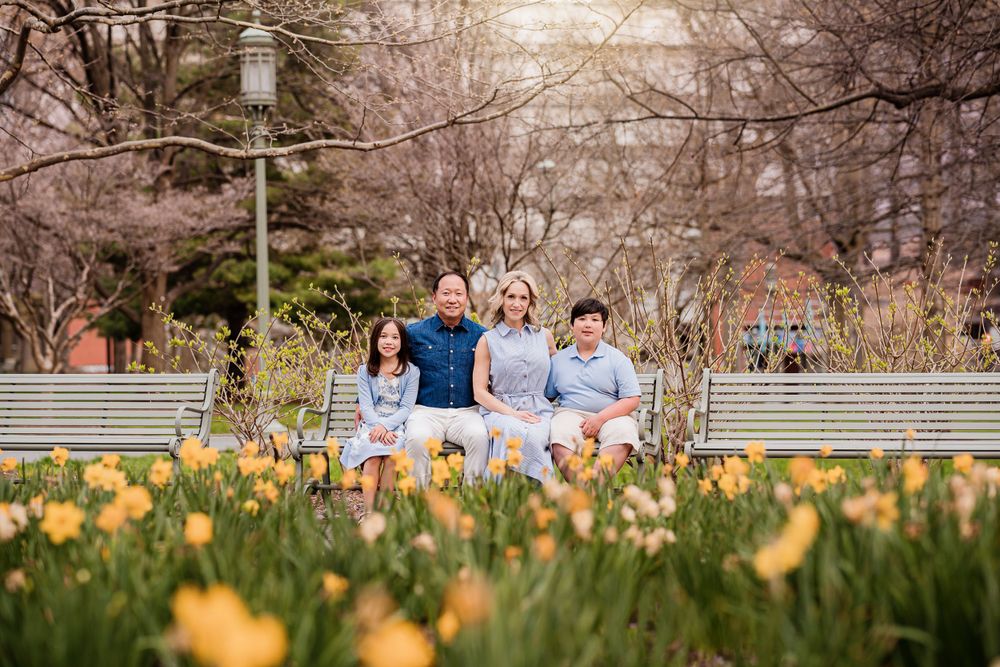 Family sitting on steps among blooming yellow tulips in springtime garden setting.