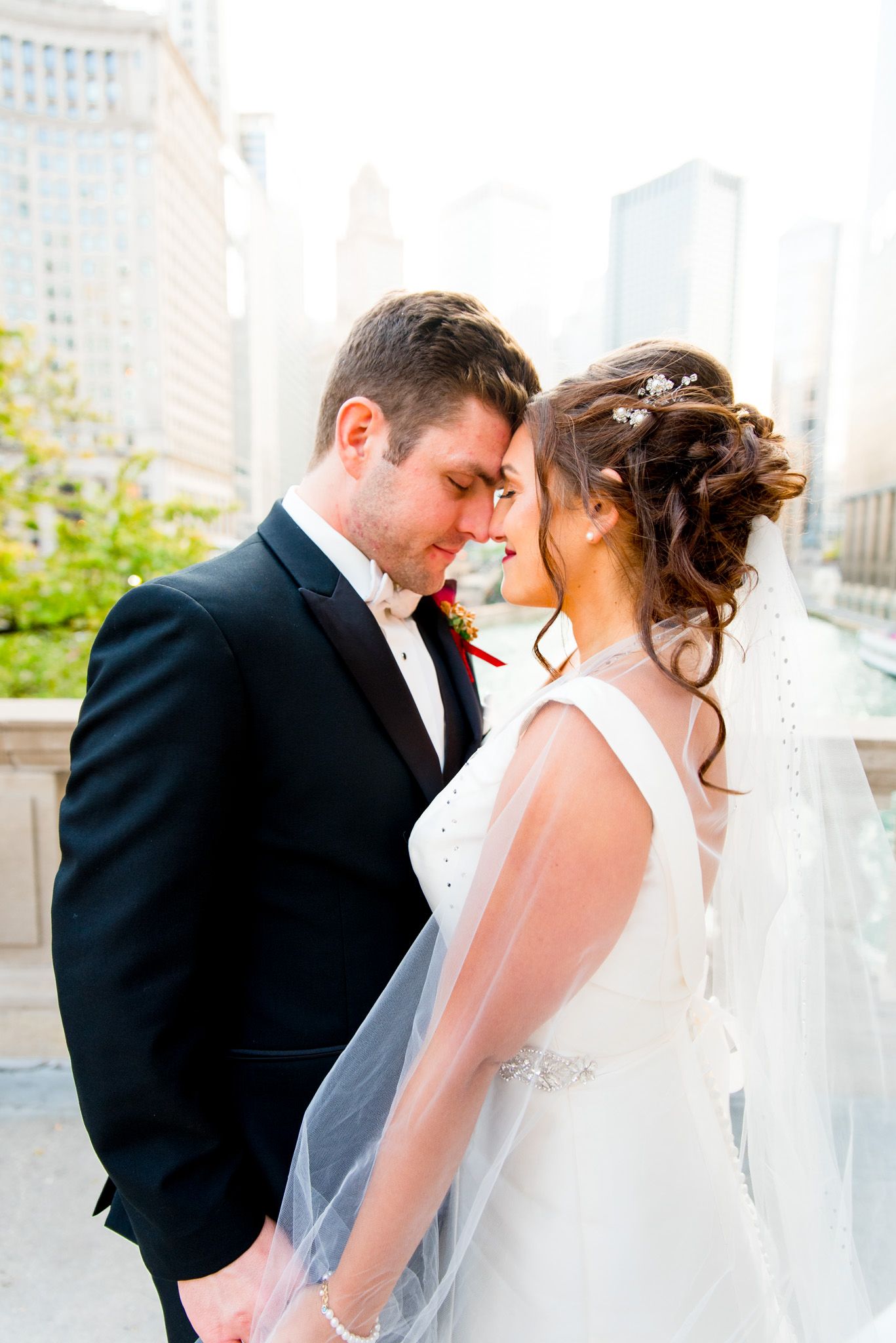 bride and groom caress on bridge in downtown chicago on their wedding day
