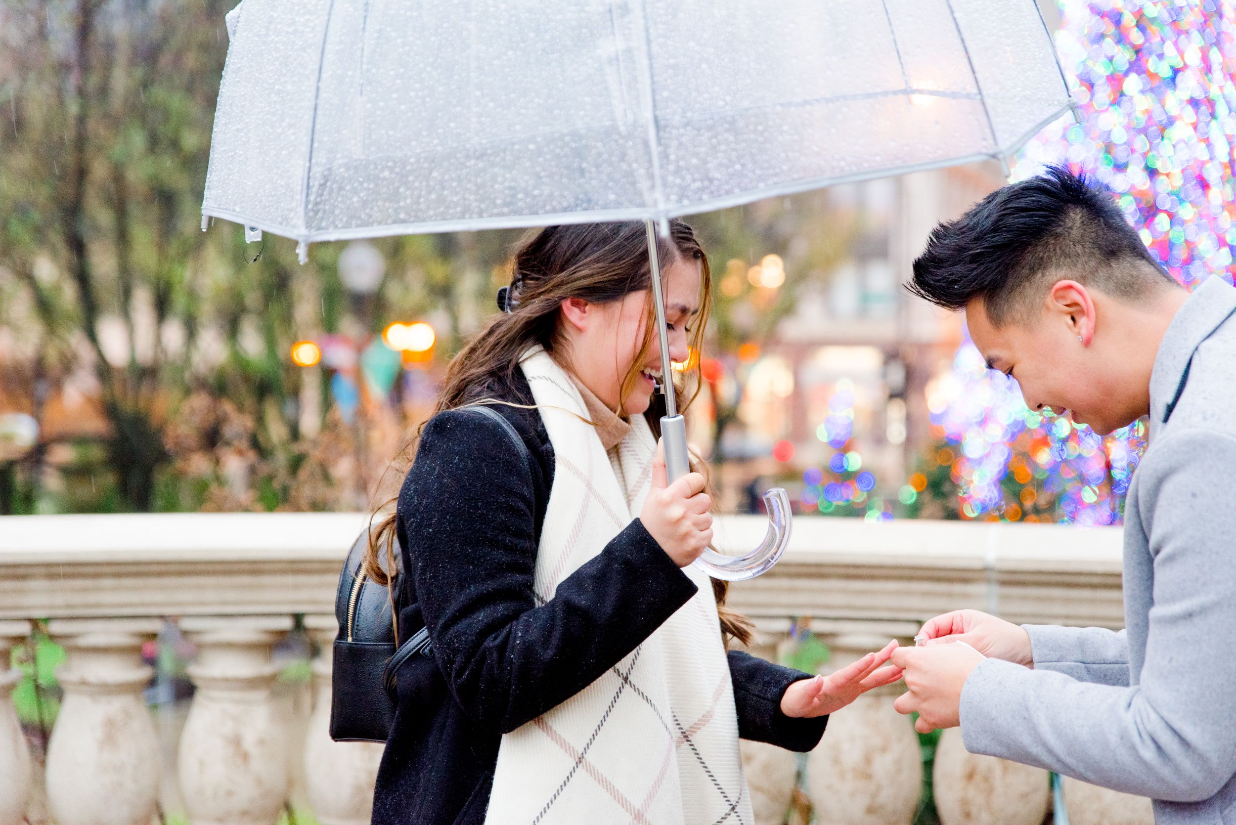 man putting engagement ring on fiance in front of Millennium Park Christmas Tree