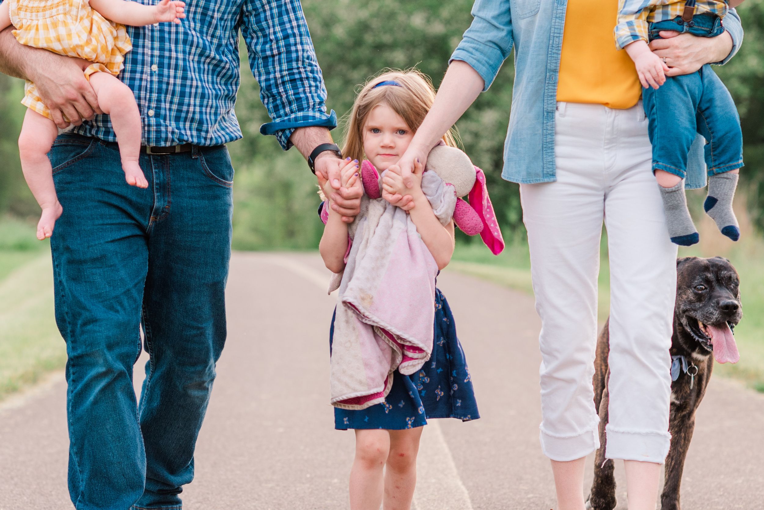 Family walking with daughter holding hands in middle at family photos at Moraine State Park, Pennsylvania