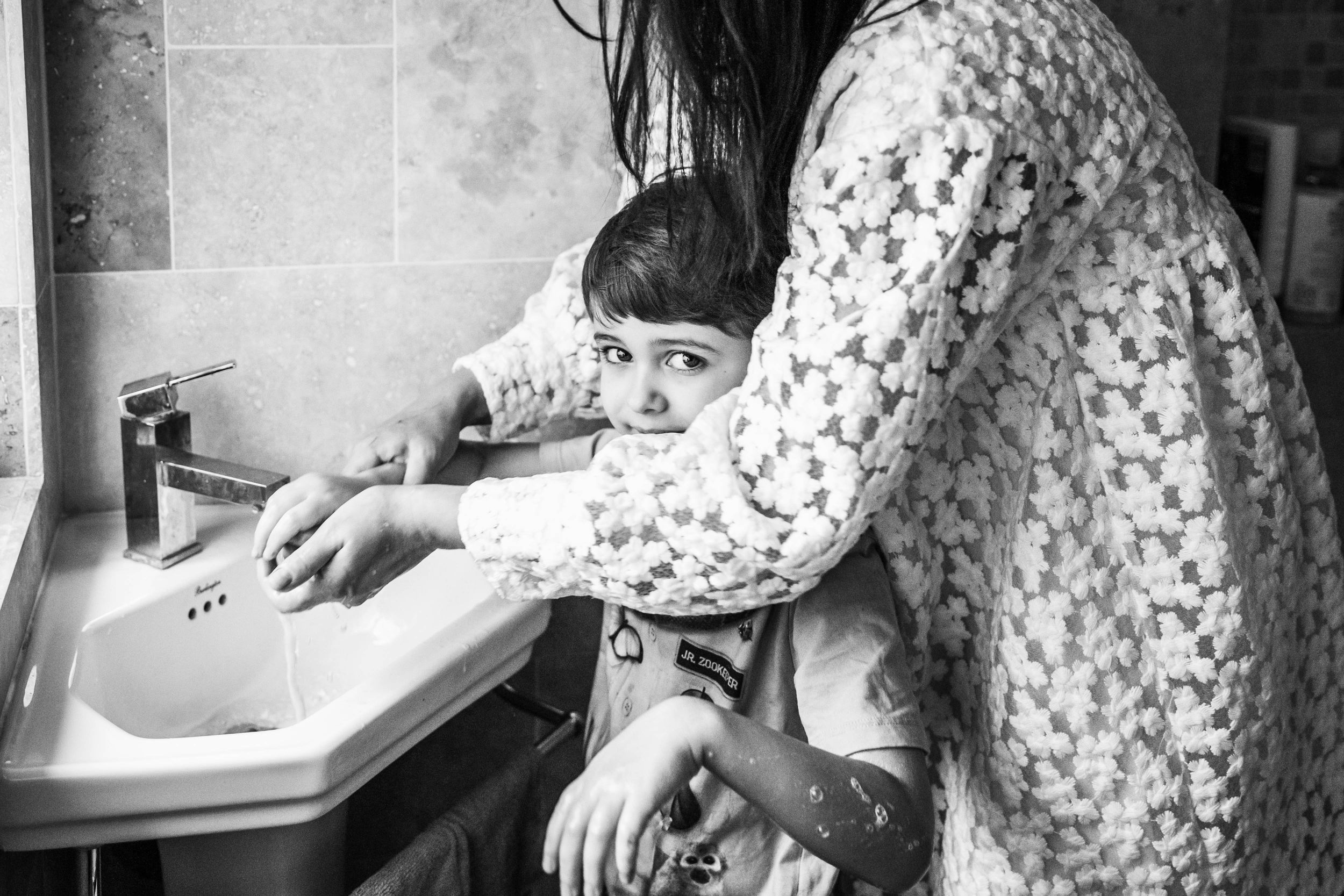 mum cleaning boy hands in bathroom black and white