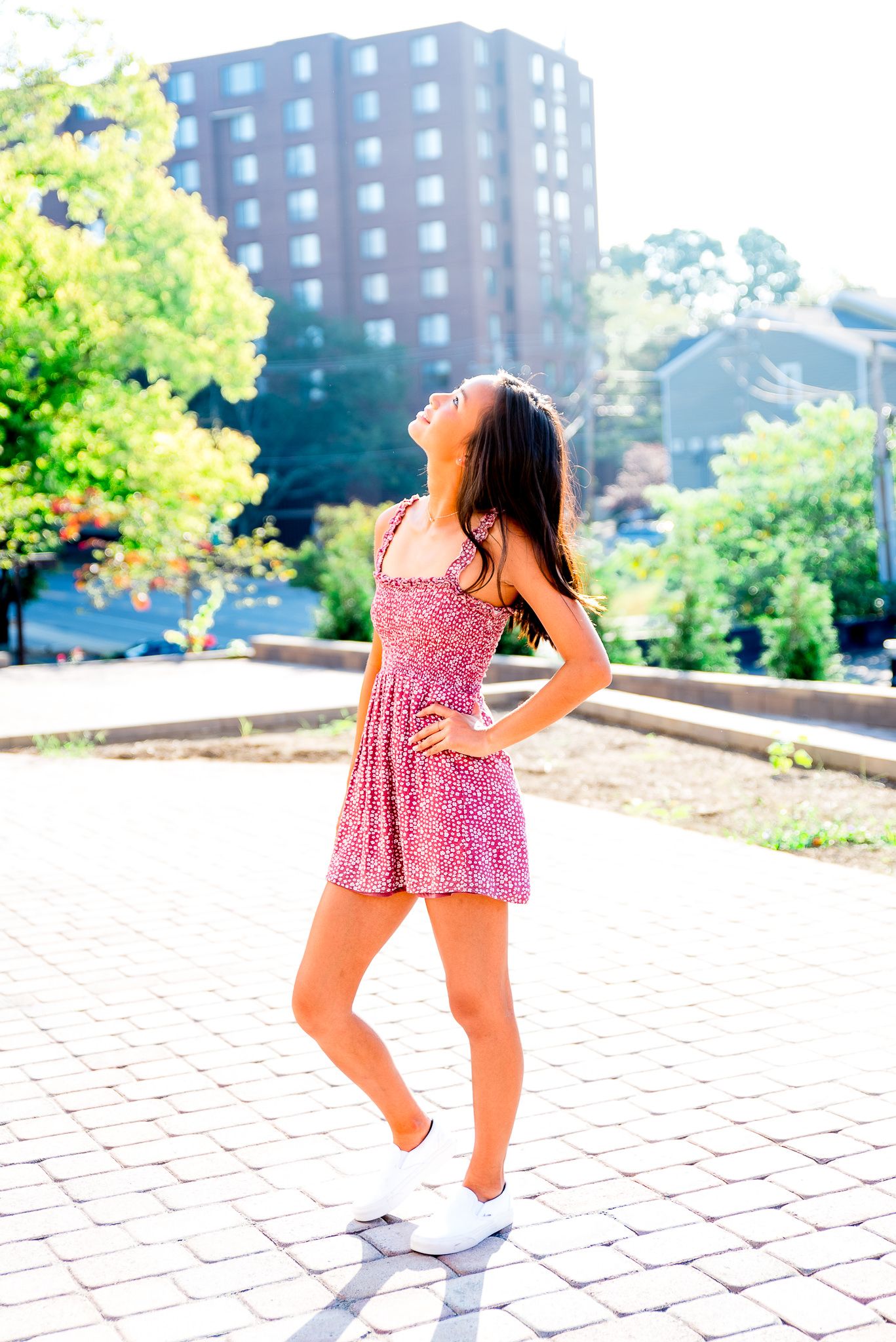 high school senior girl in red dress with hand on hip looking to the sky