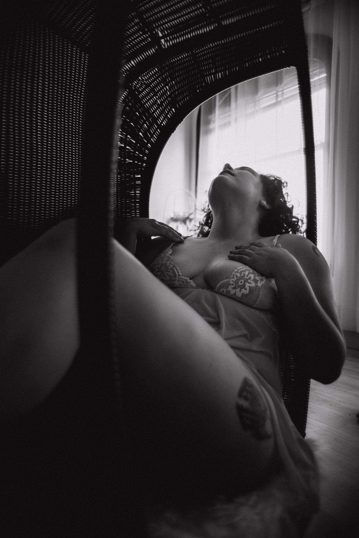 woman in lingerie posing for boudoir photos in wicker egg chair