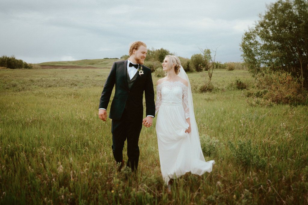 A couple shares a romantic moment in a grassy field during their wedding photoshoot.