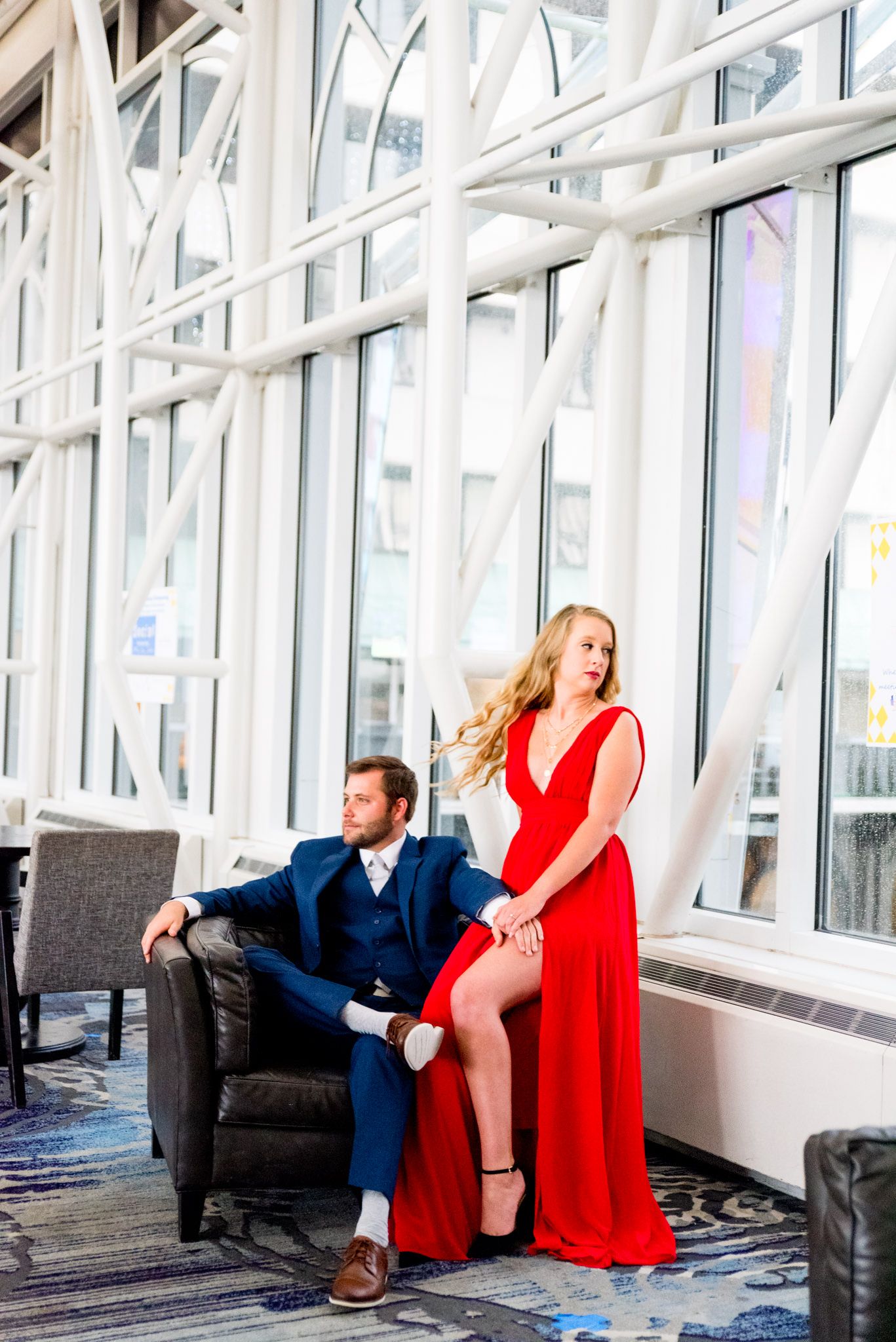 blonde woman in red dress sitting with fiance in navy suit at Galt House Hotel engagement pictures