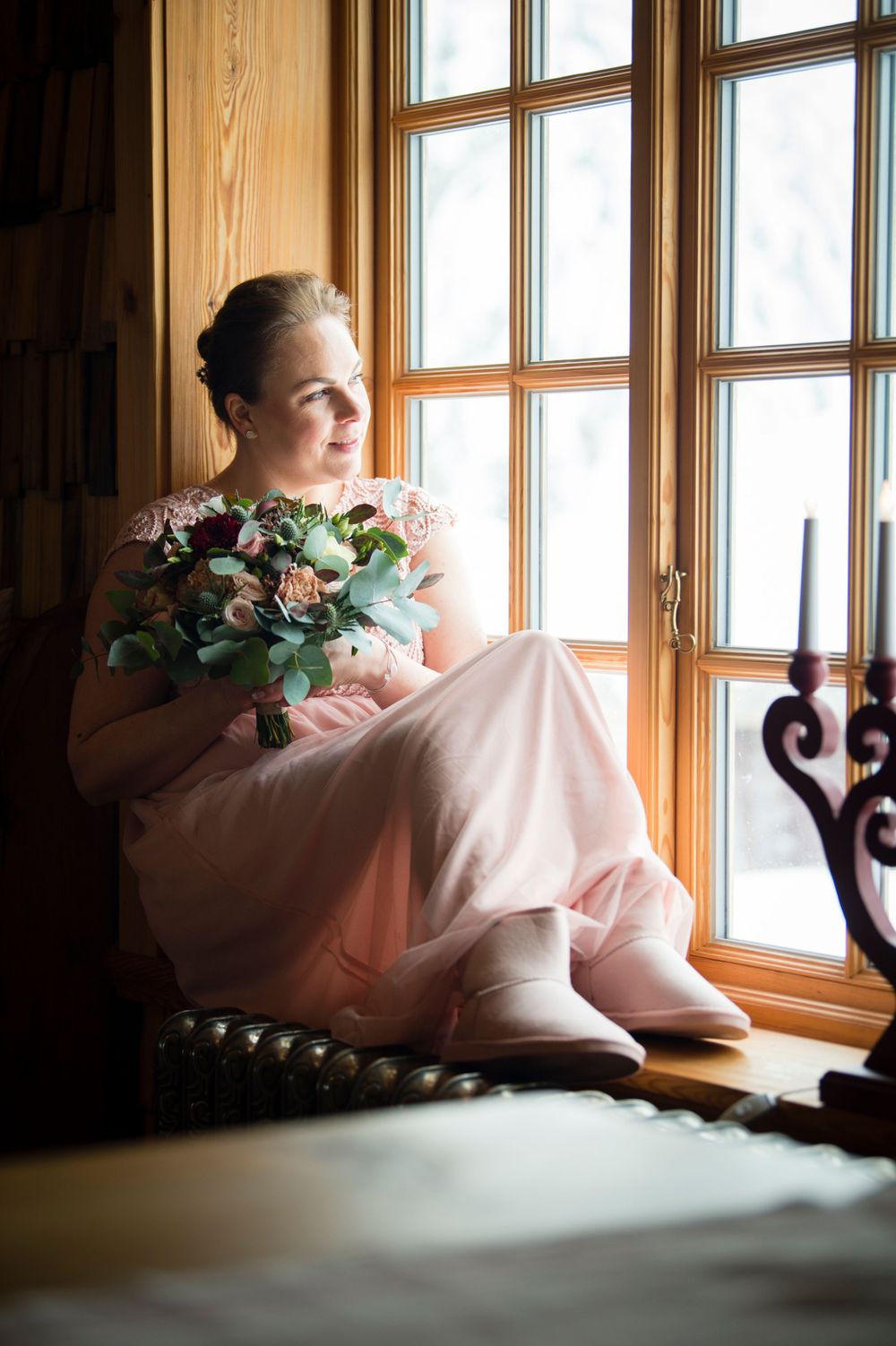 Brud i rosa klänning sittandes i fönster