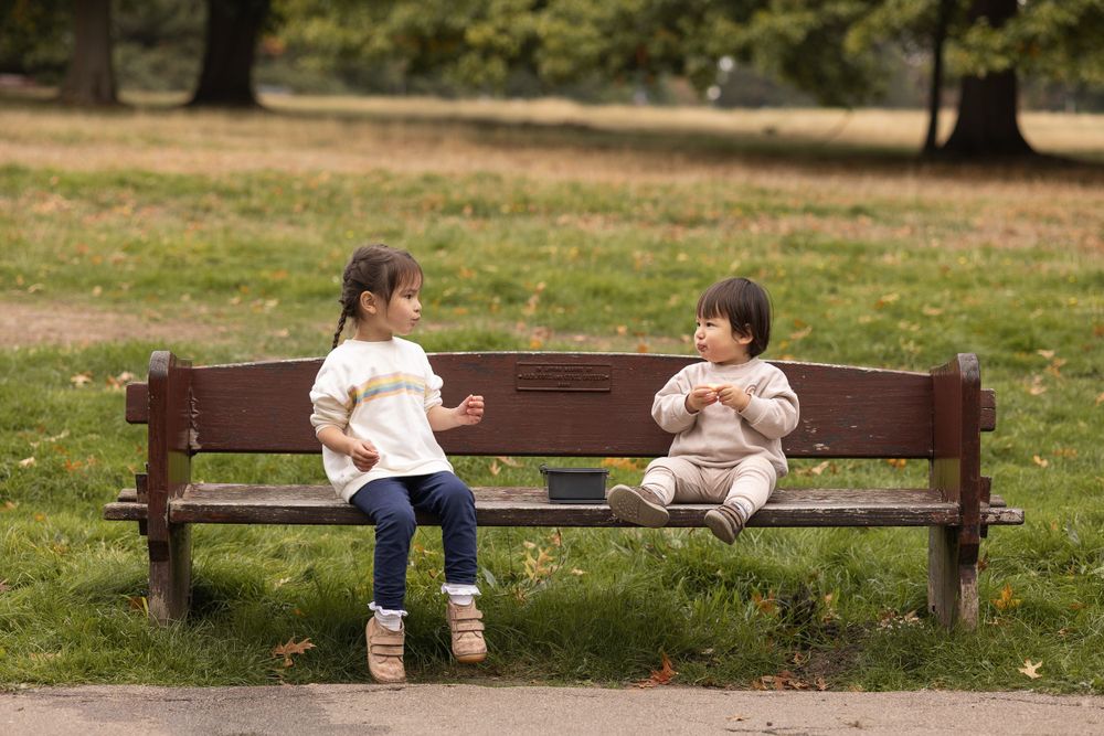Siblings sitting on a bench eating apples during family photoshoot