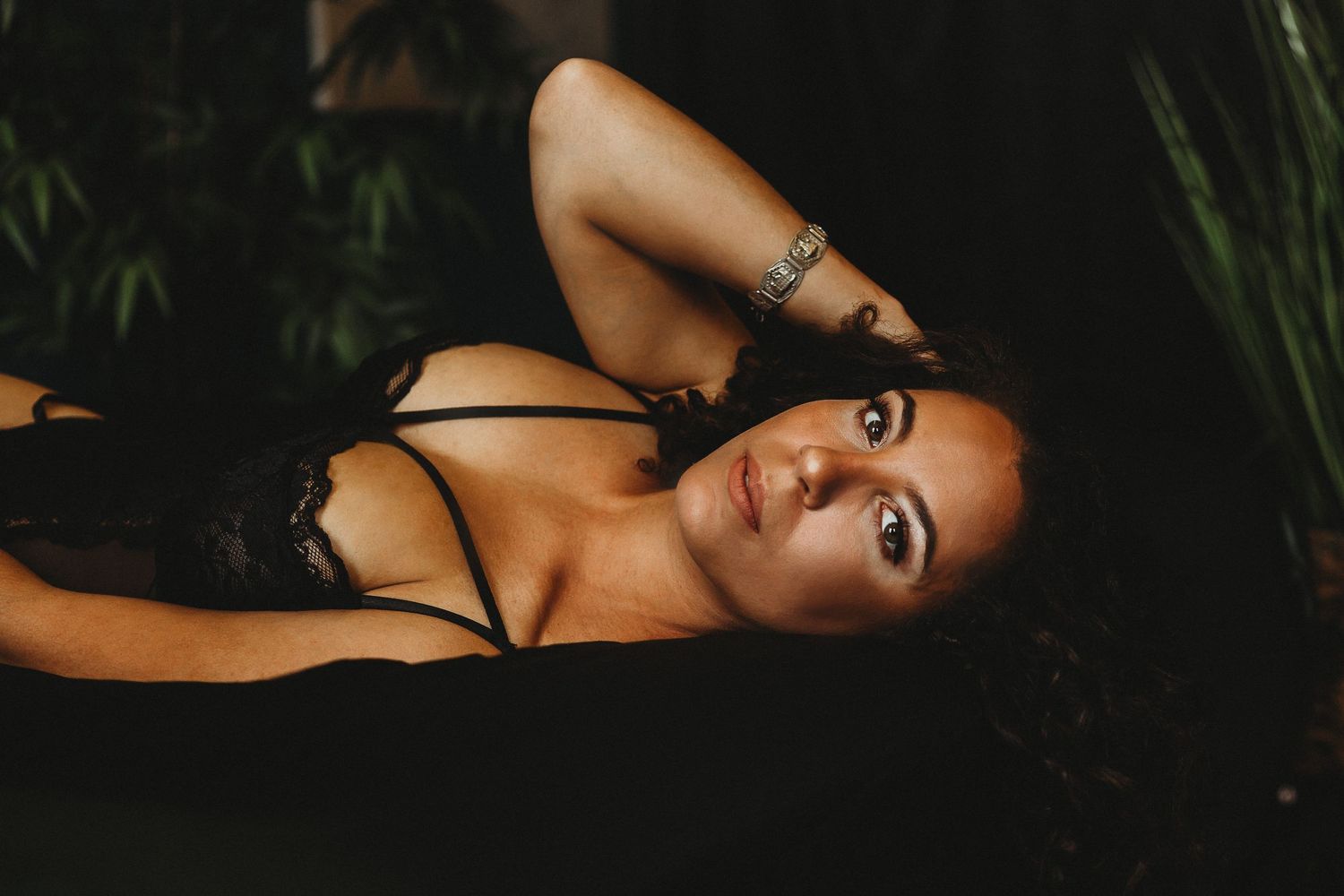Artistic boudoir photo in natural setting with moody lighting and black lingerie.
