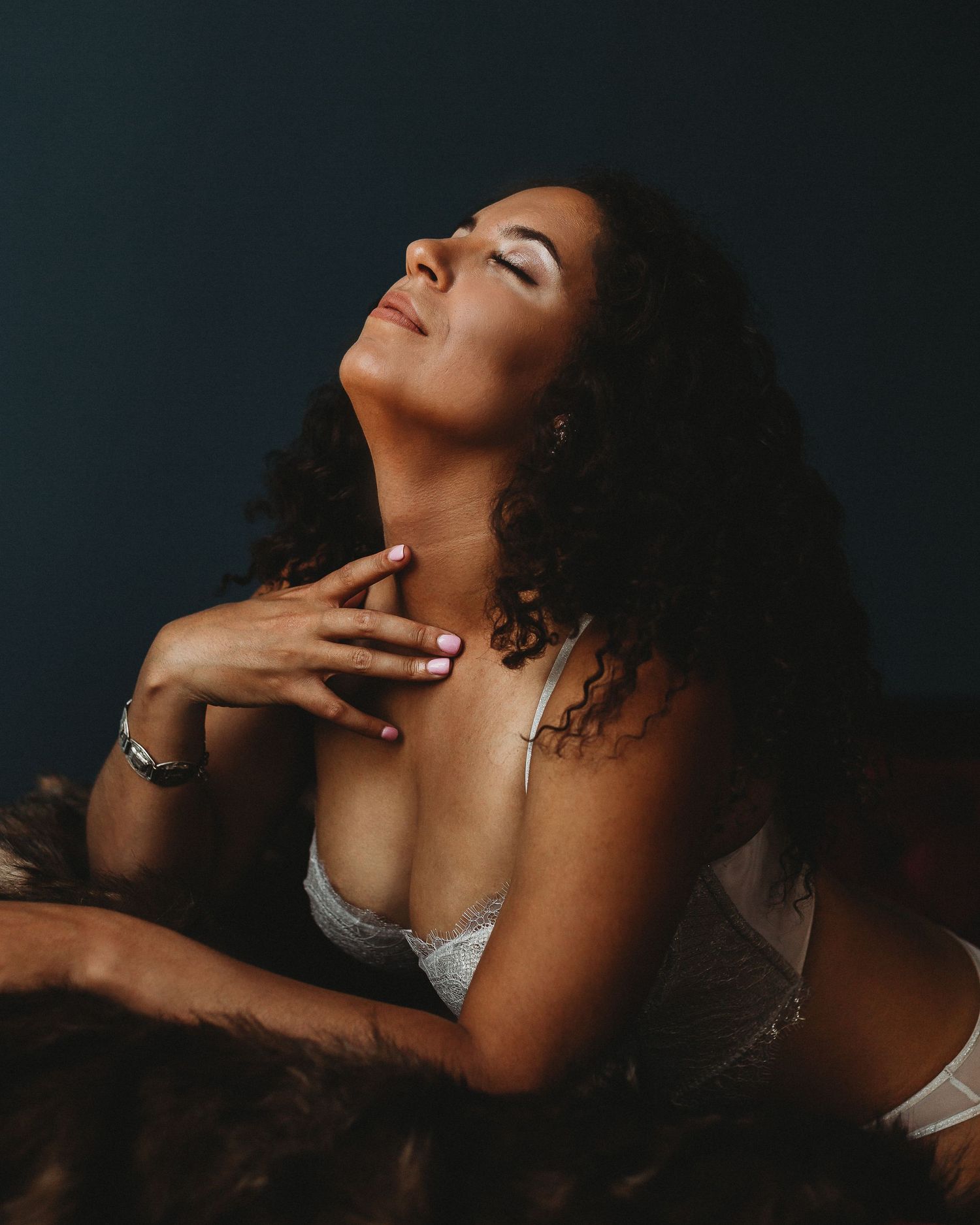 Atmospheric boudoir portrait with dramatic lighting and white lace lingerie.