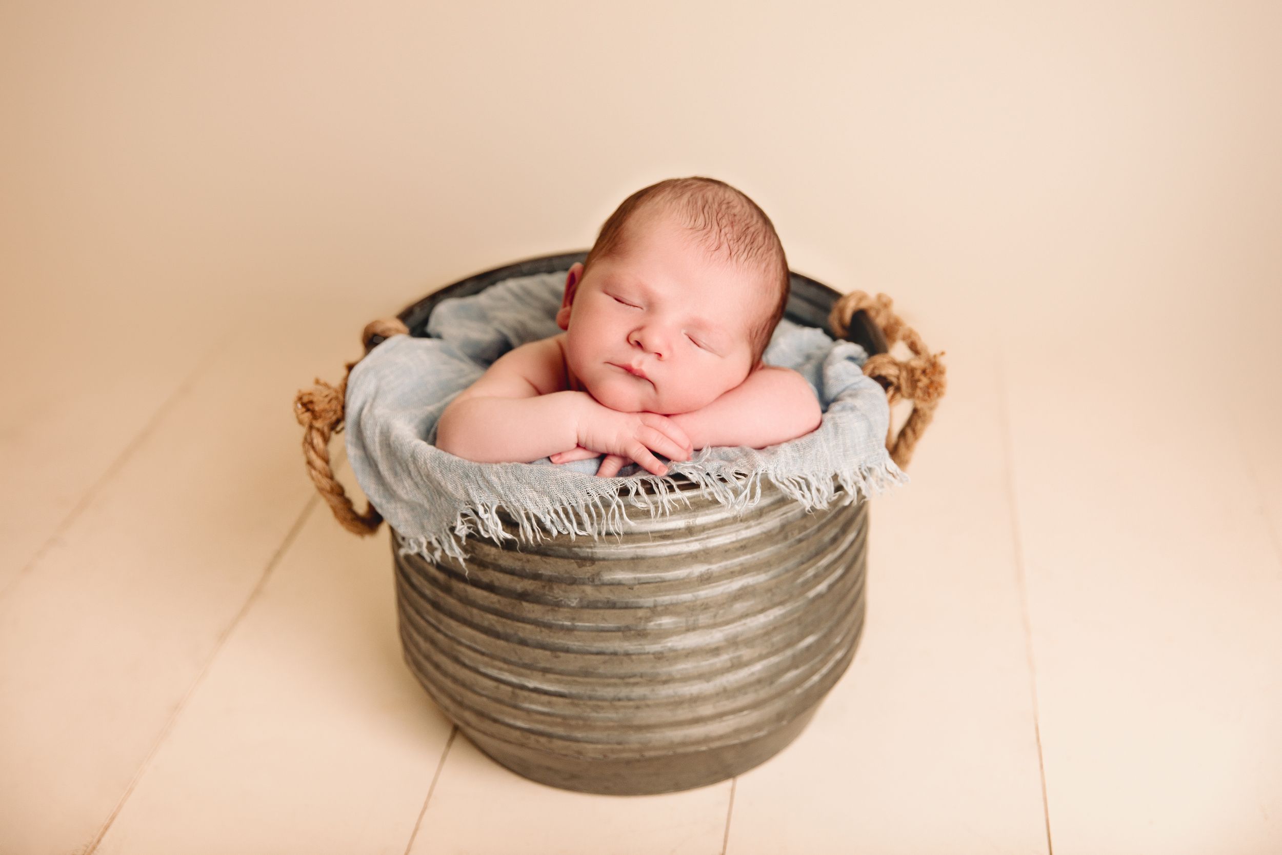 baby sleeping in galvanized bucket his chin resting on his hands