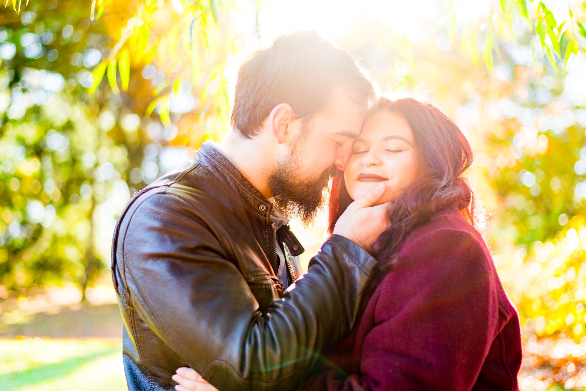 brown hair man holding woman with red hair in matching red coat, smiling at sunrise in Central Park
