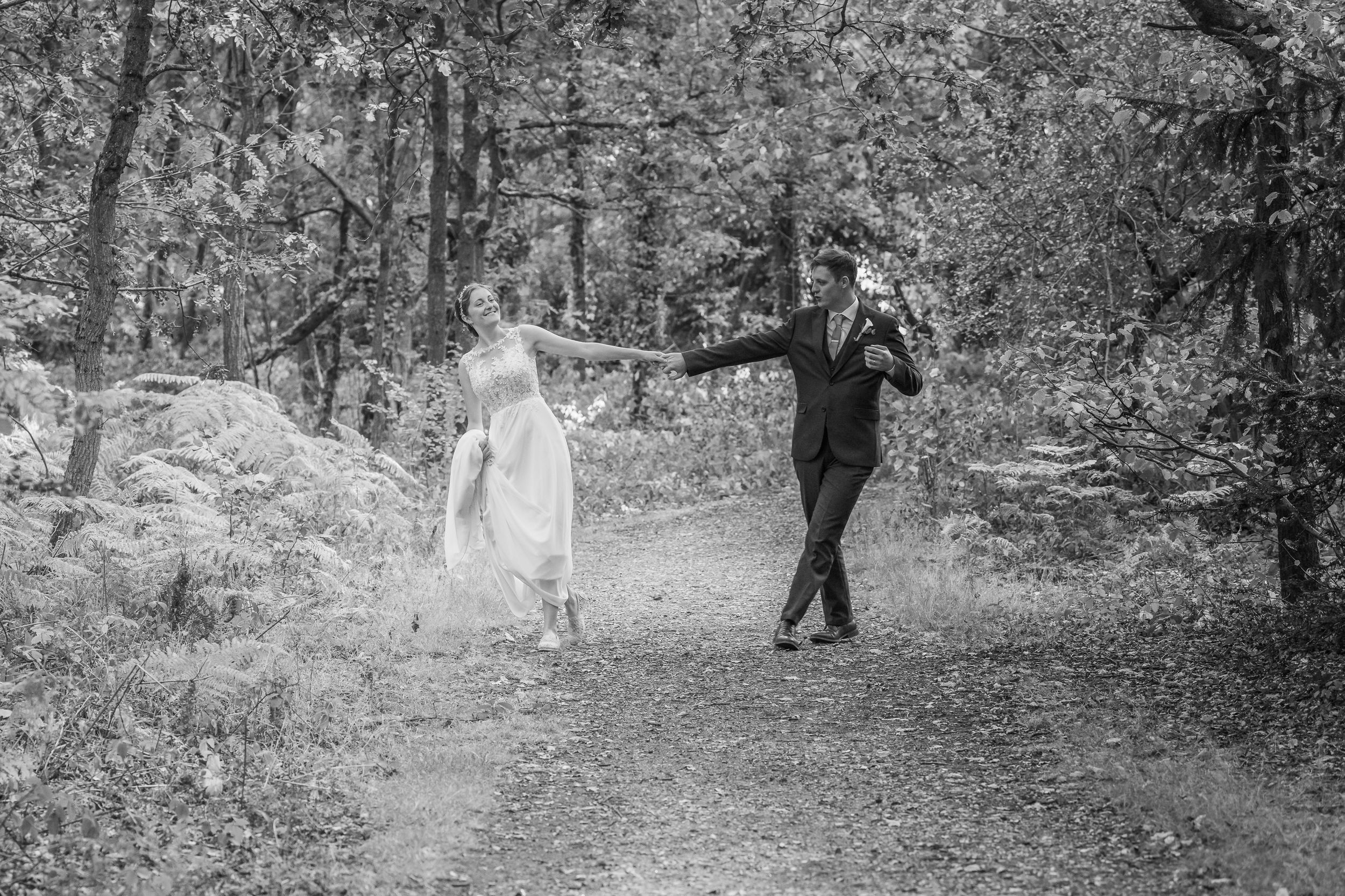 Bride and groom walking and dancing through the forrest