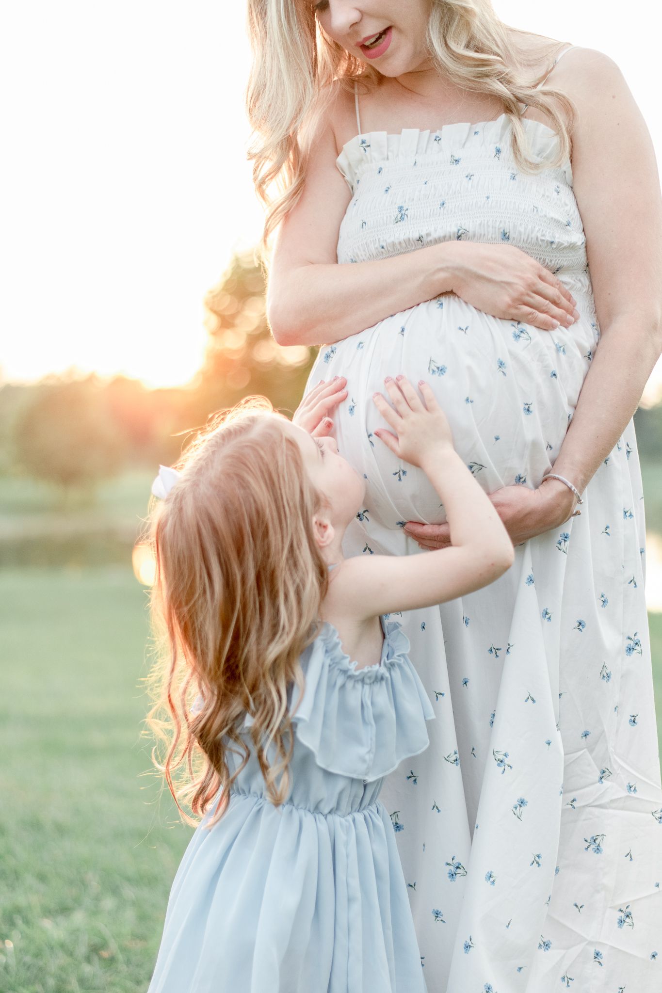 Little girl kisses her pregnant mother's stomach