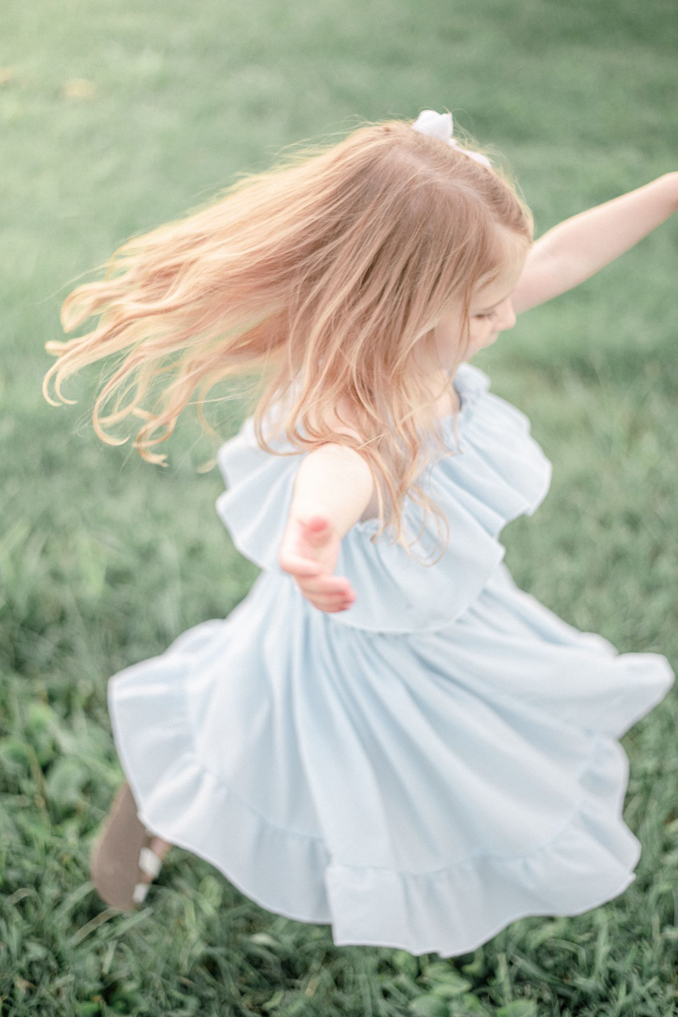 Little girl twirls as her dress flies around her at sunset