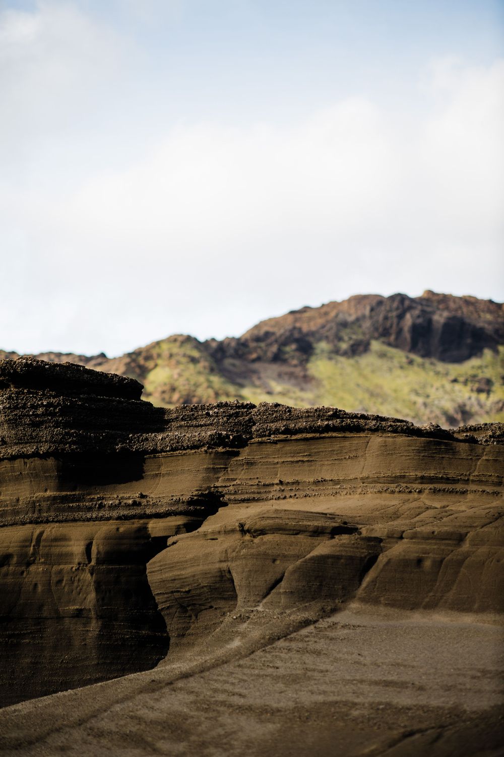 Layered rock formations in desert landscape under cloudy sky.