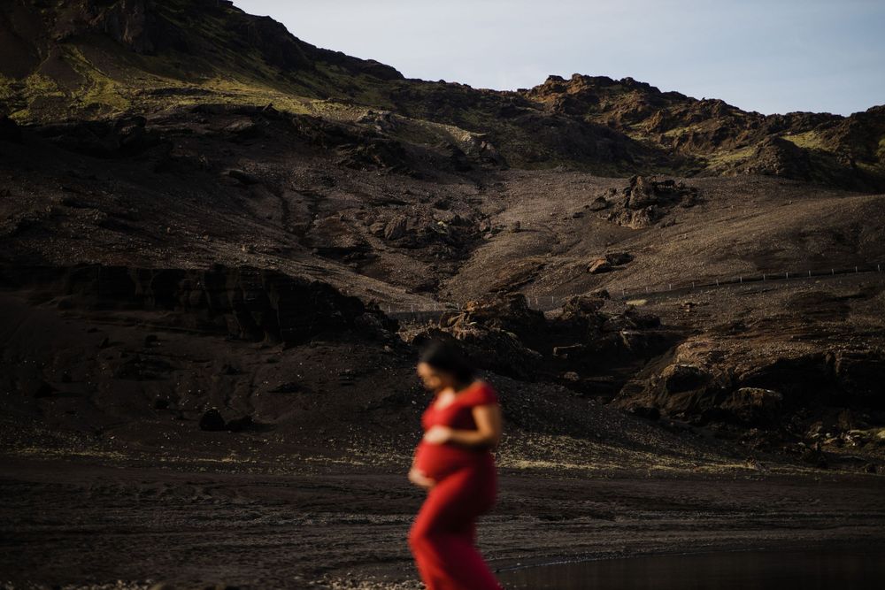 Silhouette in red dress against dramatic mountain landscape.