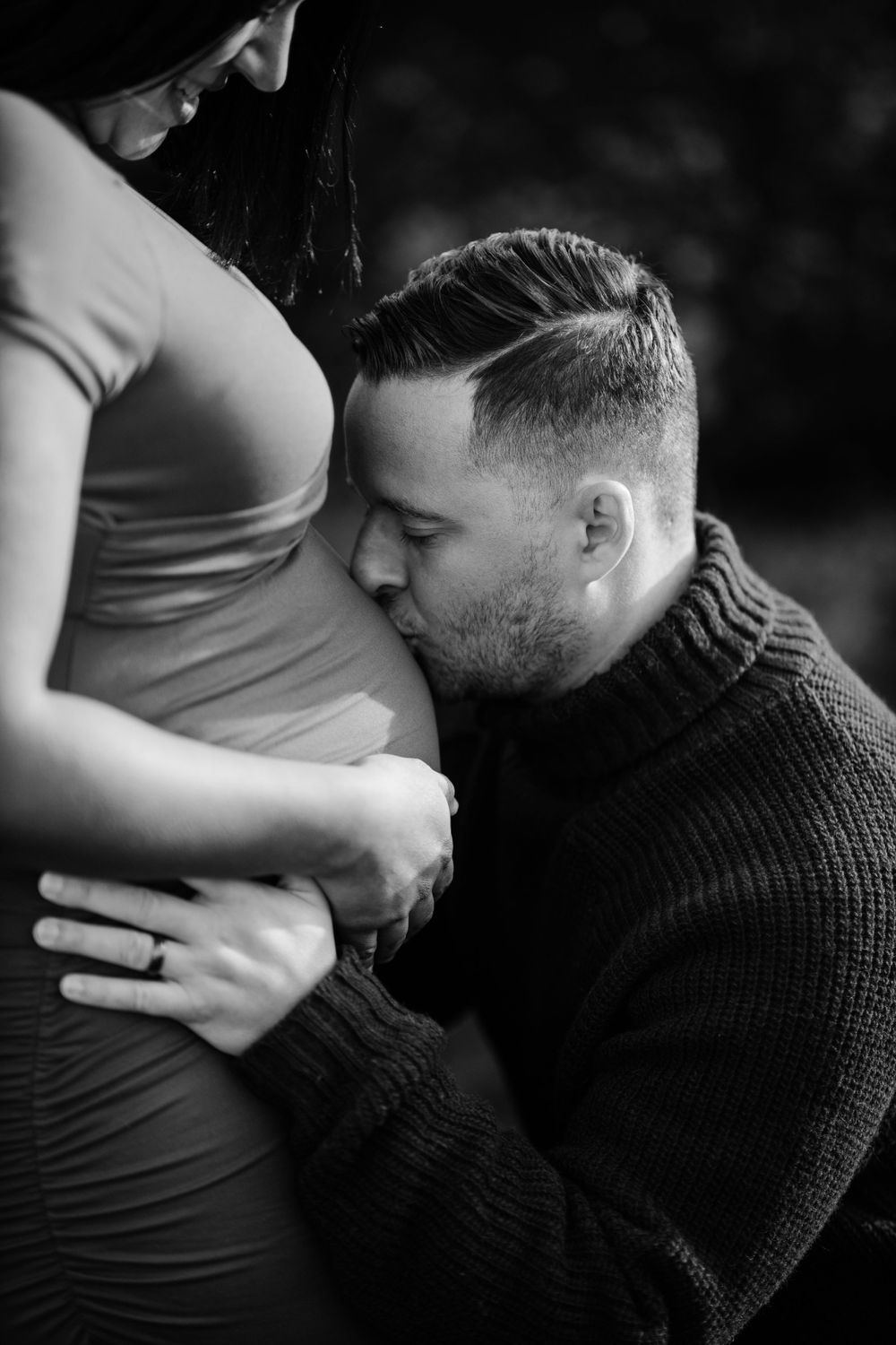 Tender black and white maternity moment between couple.