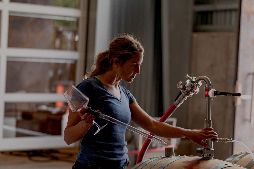 Woman Winemaker Portrait. Wynne Solomon racking wine in the cellar at Peake Ranch Vineyard