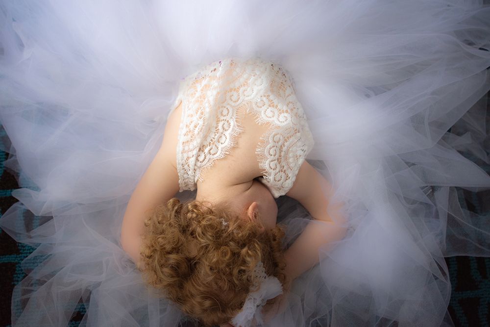 flower girl laying on the floor surrounded by tulle