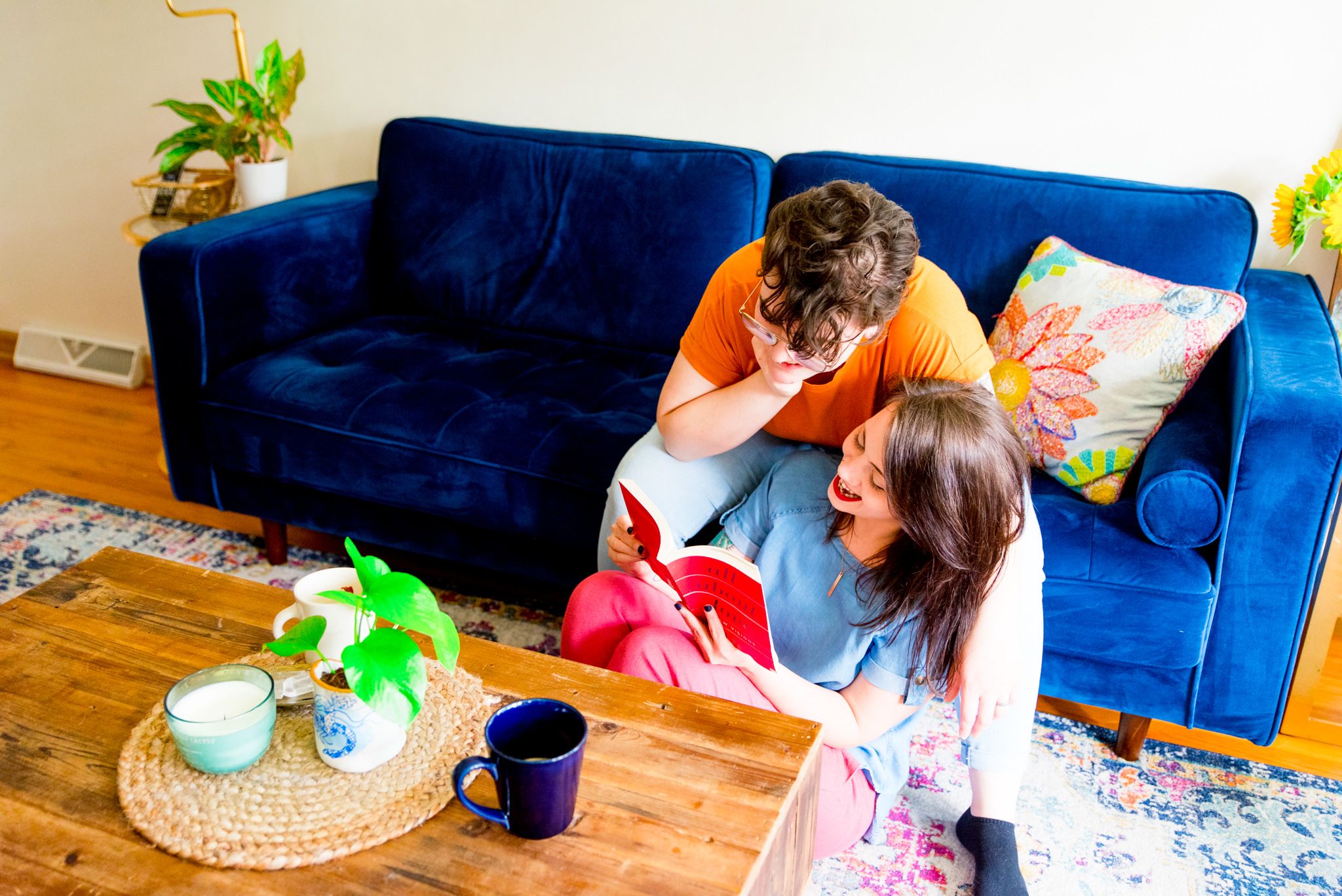 woman sitting on floor reading book to wife sitting on blue couch for chicago couples pictures