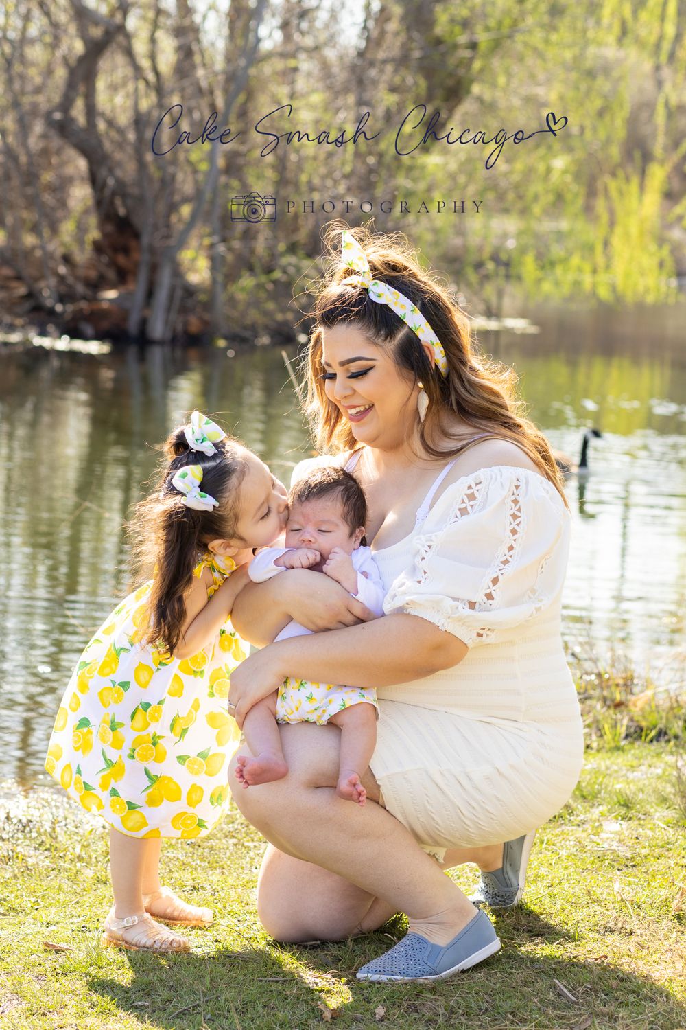 Intimate family photo by a pond showing joyful interaction between mother and children.