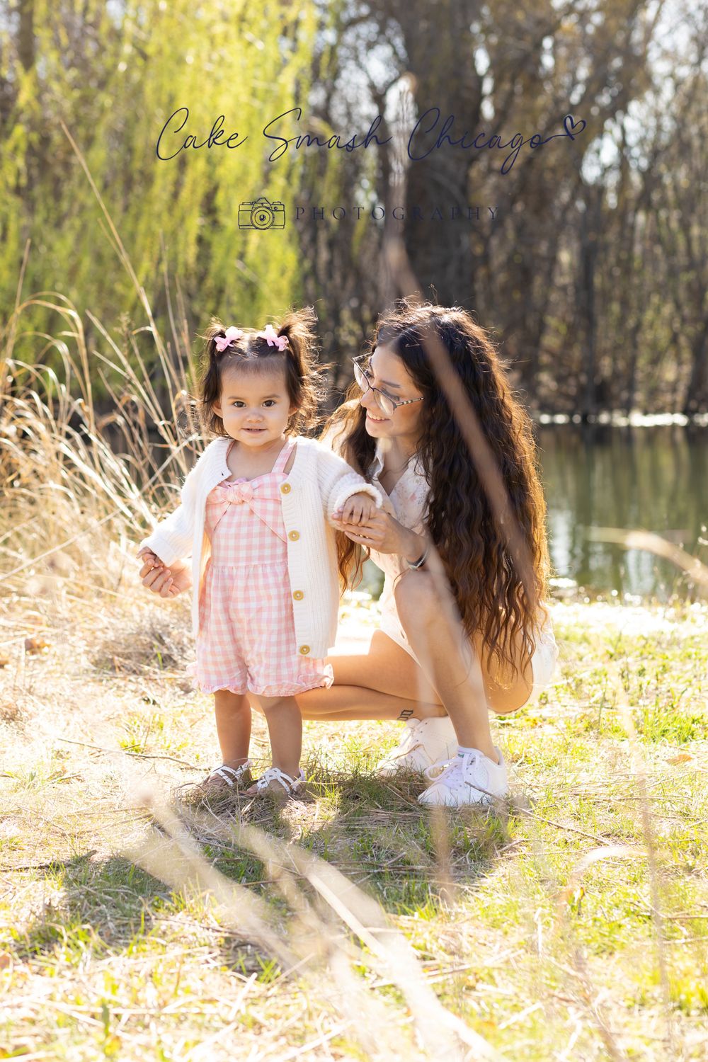 Mother and child share a sweet moment outdoors by a lake in spring sunshine.