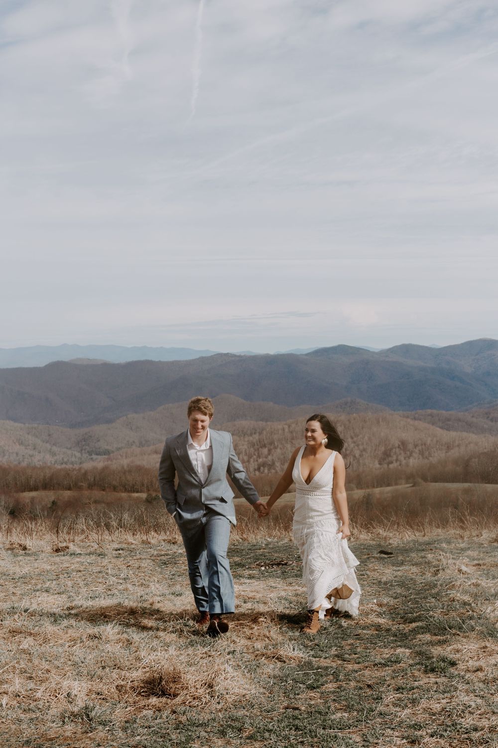 couple running up a hill in the North Carolina mountains during their full day elopement