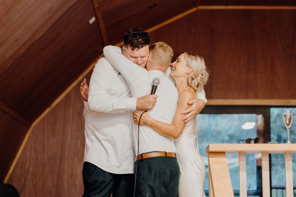 Three people sharing an intimate moment during a celebration in a wooden interior.