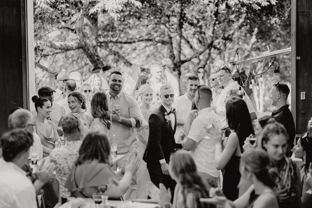 Black and white reception photo showing guests celebrating at outdoor wedding.