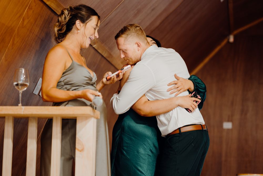 People sharing an emotional moment during a celebration in a rustic interior.