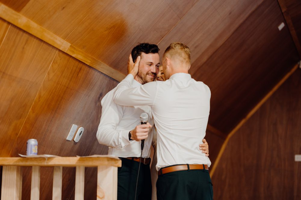 Two people hugging and sharing a drink in a wooden-paneled room.