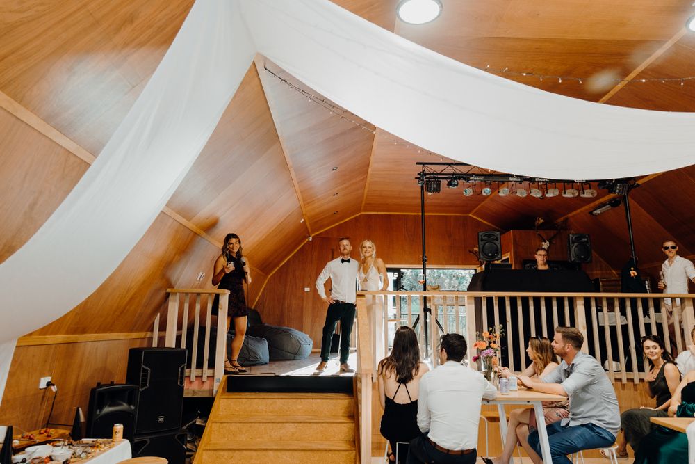 Wedding reception venue with draped fabric ceiling and wooden dance floor.