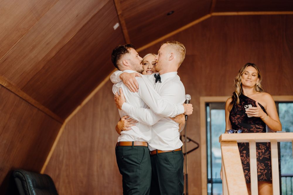 People sharing emotional embraces during a celebration in a rustic venue.