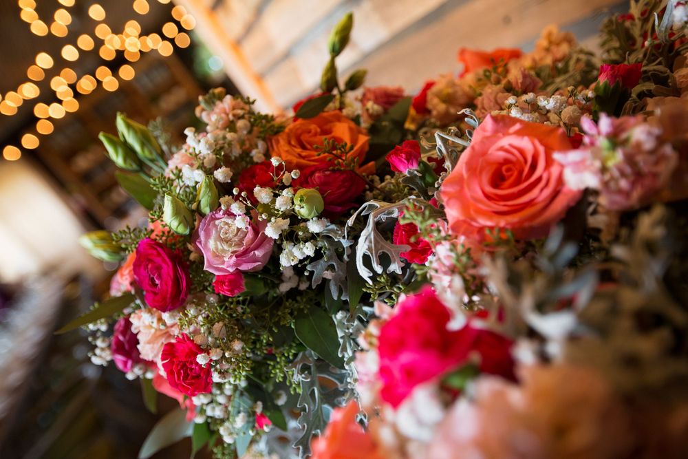 Vibrant floral centerpiece with pink and red roses against bokeh lights background.