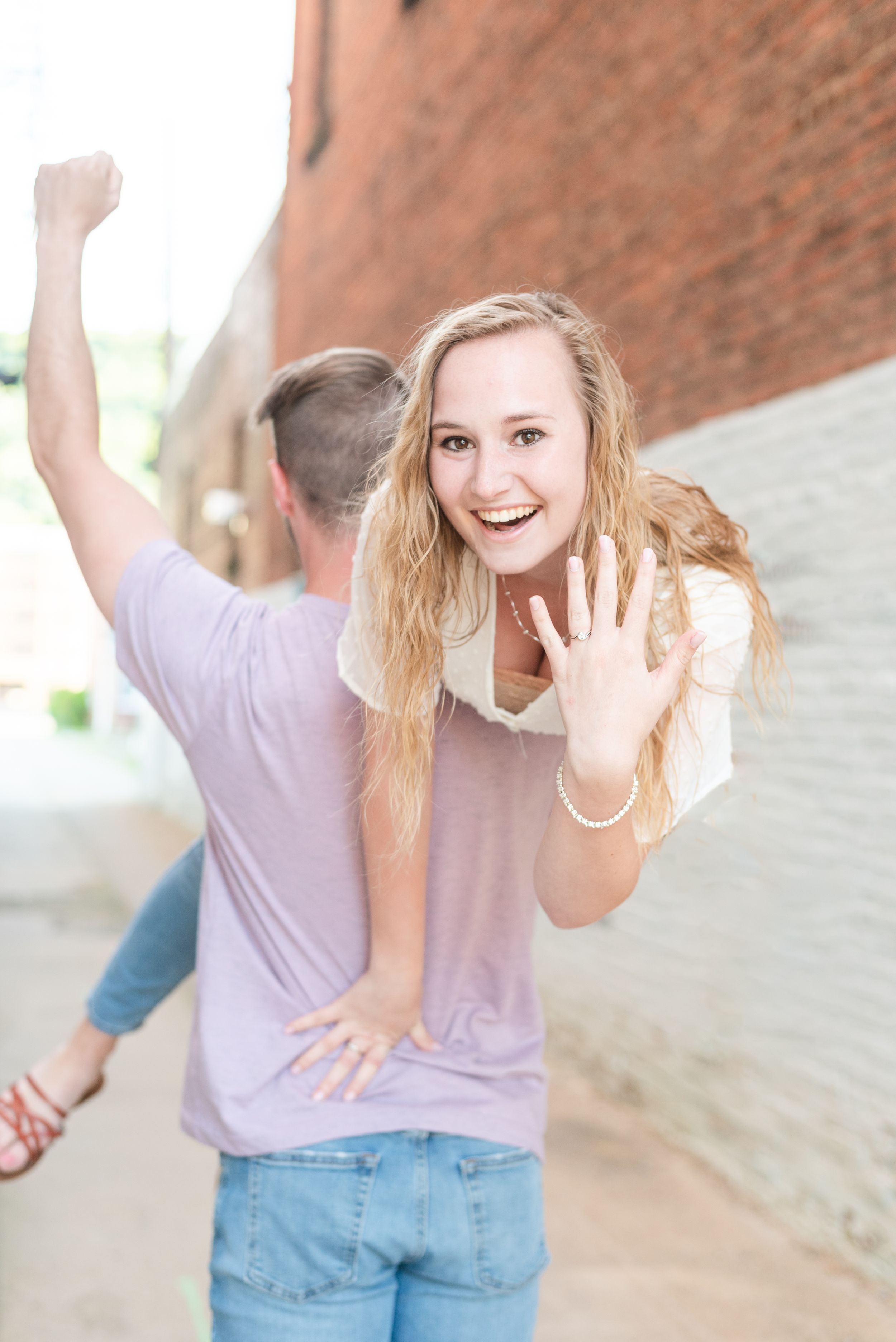 Girl thrown over boy's shoulder showing off engagement ring in alley in Franklin Pennsylvania